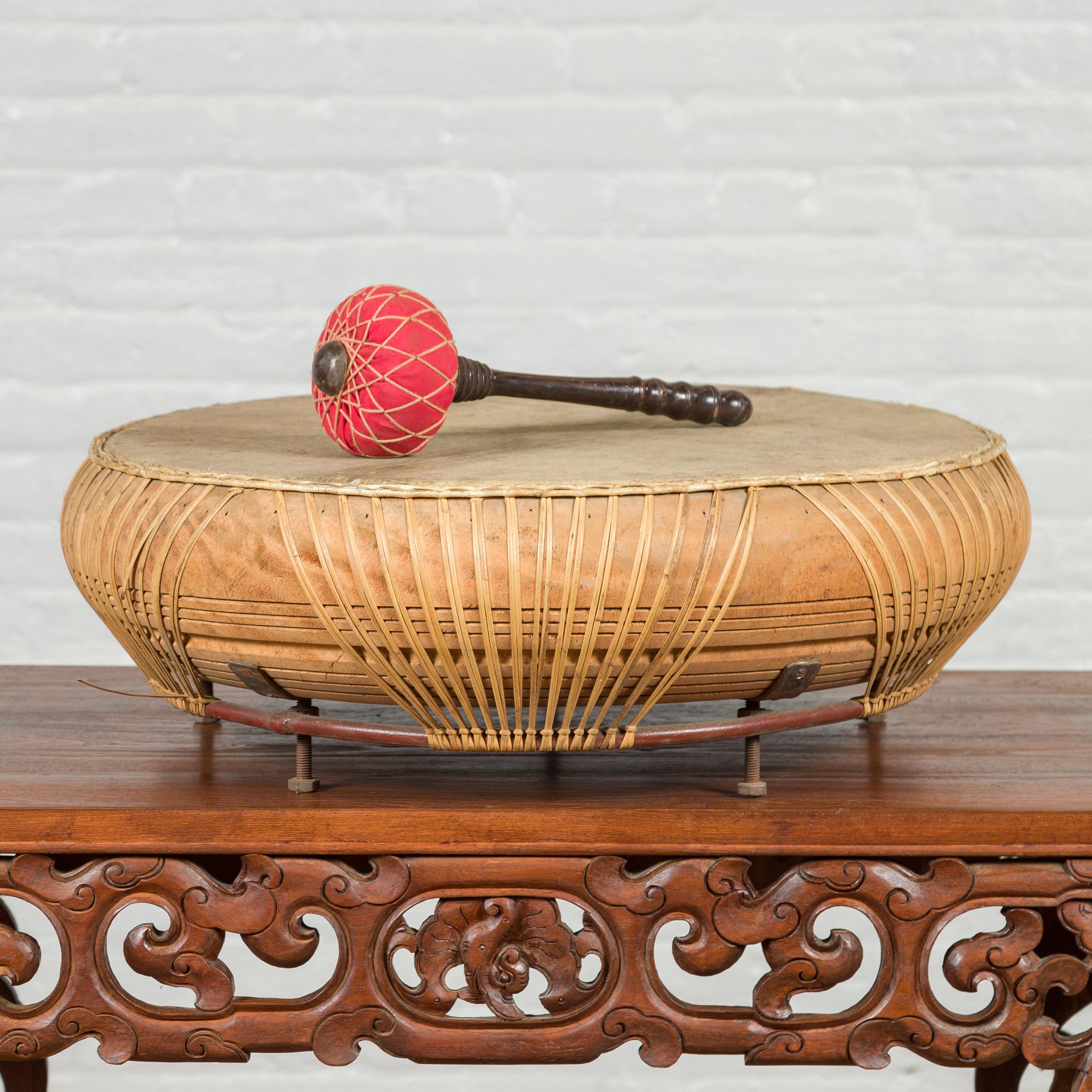A Chinese Qing dynasty period leather drum from the 19th century, with turned wood red mallet. Created in China during the Qing dynasty, this round leather drum will make for an exquisite decorative accent in any home. Freestanding, it comes with