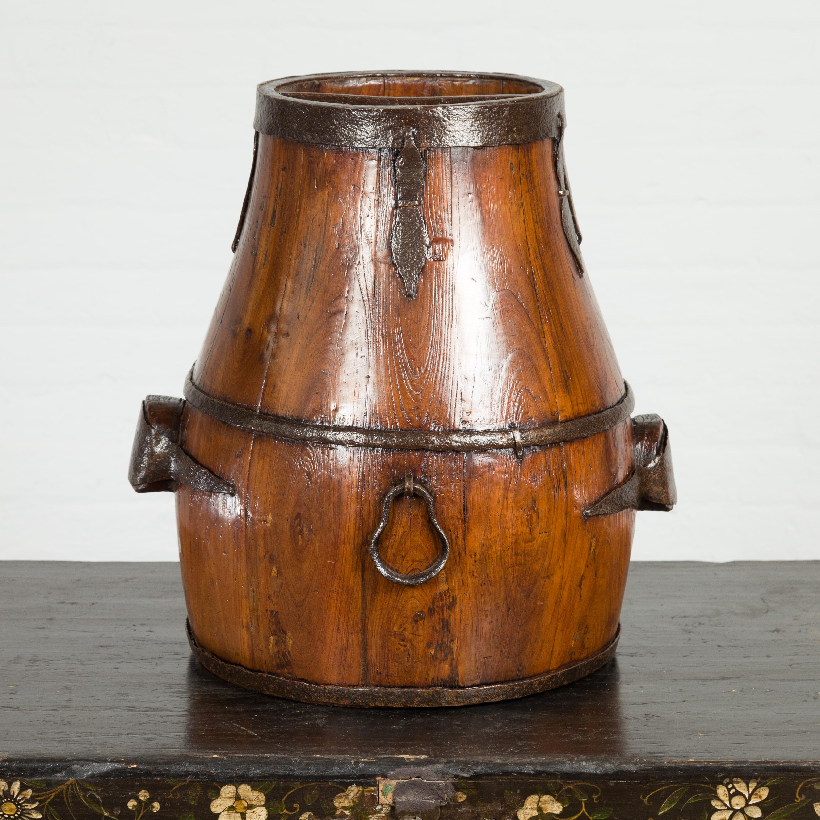 An antique Chinese Qing Dynasty period handmade pear shaped wooden grain basket from the 19th century, with varnished finish and iron hardware. Created in China during the Qing Dynasty period in the 19th century, this handmade grain basket features