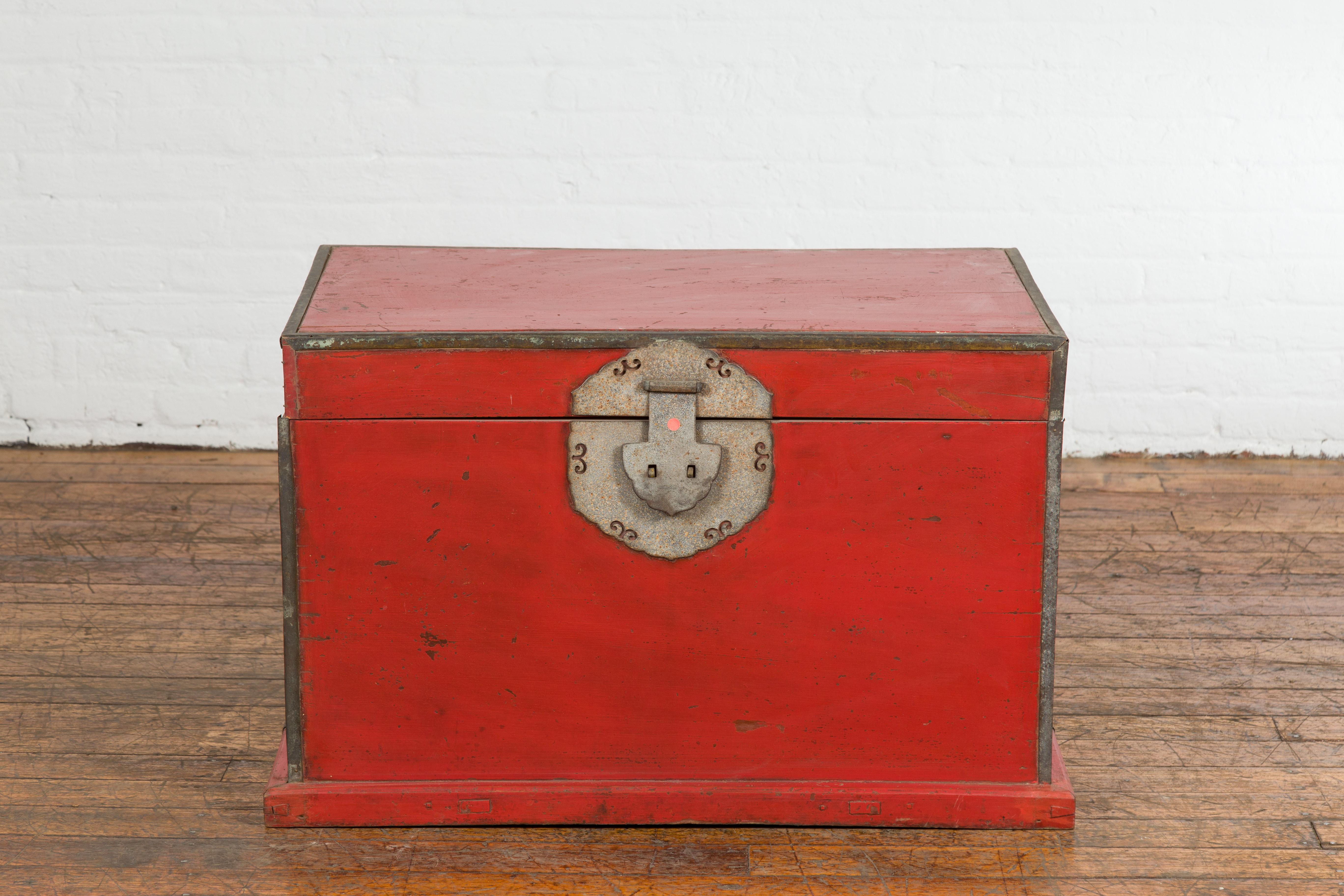 A Chinese Qing Dynasty period red lacquered blanket chest from the 19th century with metal edging and lateral handles. This 19th century red lacquered blanket chest is an exemplar of the Qing Dynasty period, characterized by its vibrant hue, metal