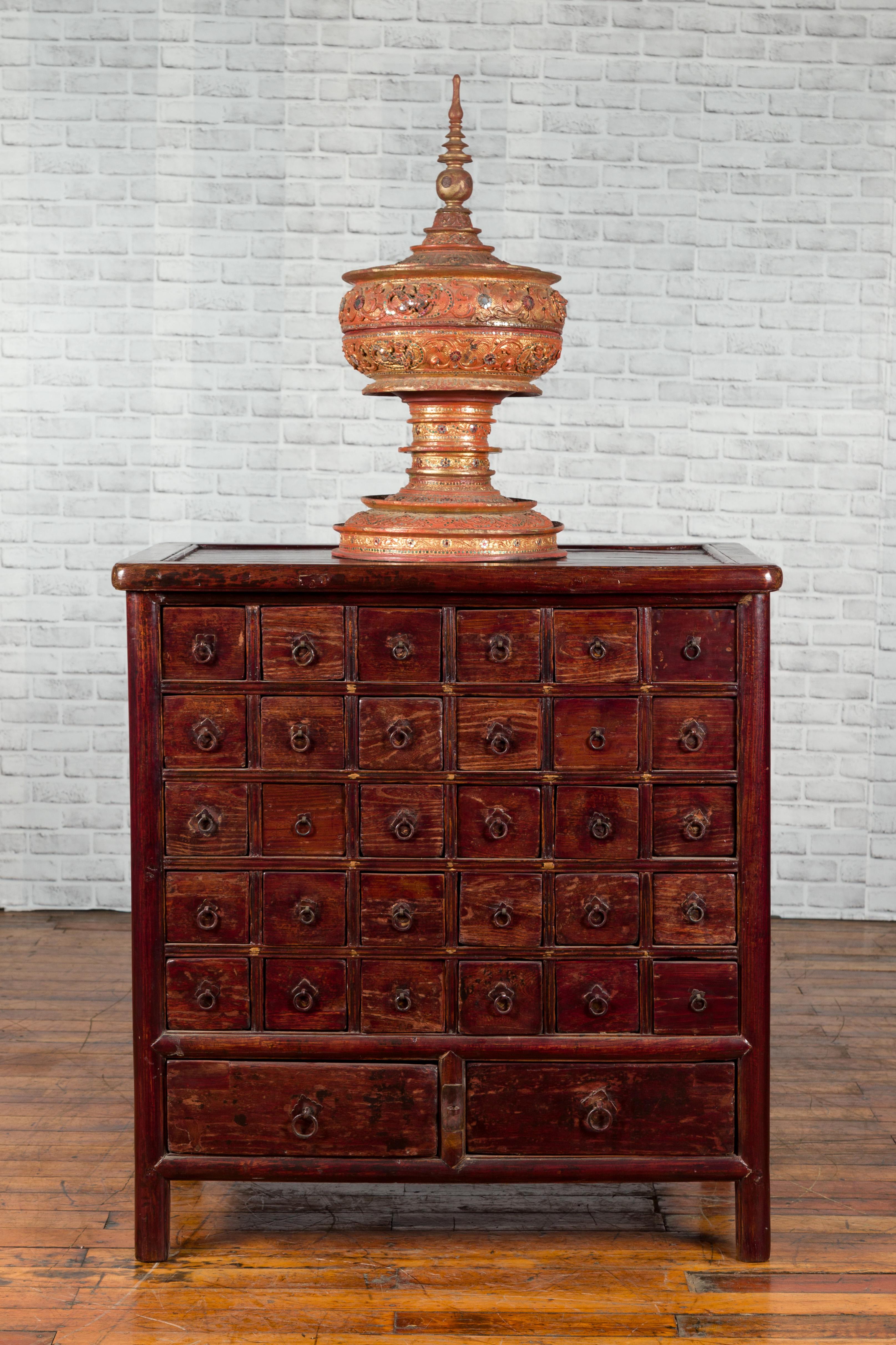 Coffre d'apothicaire chinois d'époque dynastie Qing du 19ème siècle, avec 32 tiroirs et une patine foncée. Créée en Chine sous la dynastie Qing, cette commode d'apothicaire présente un plateau rectangulaire surmontant 32 tiroirs (30 petits reposant