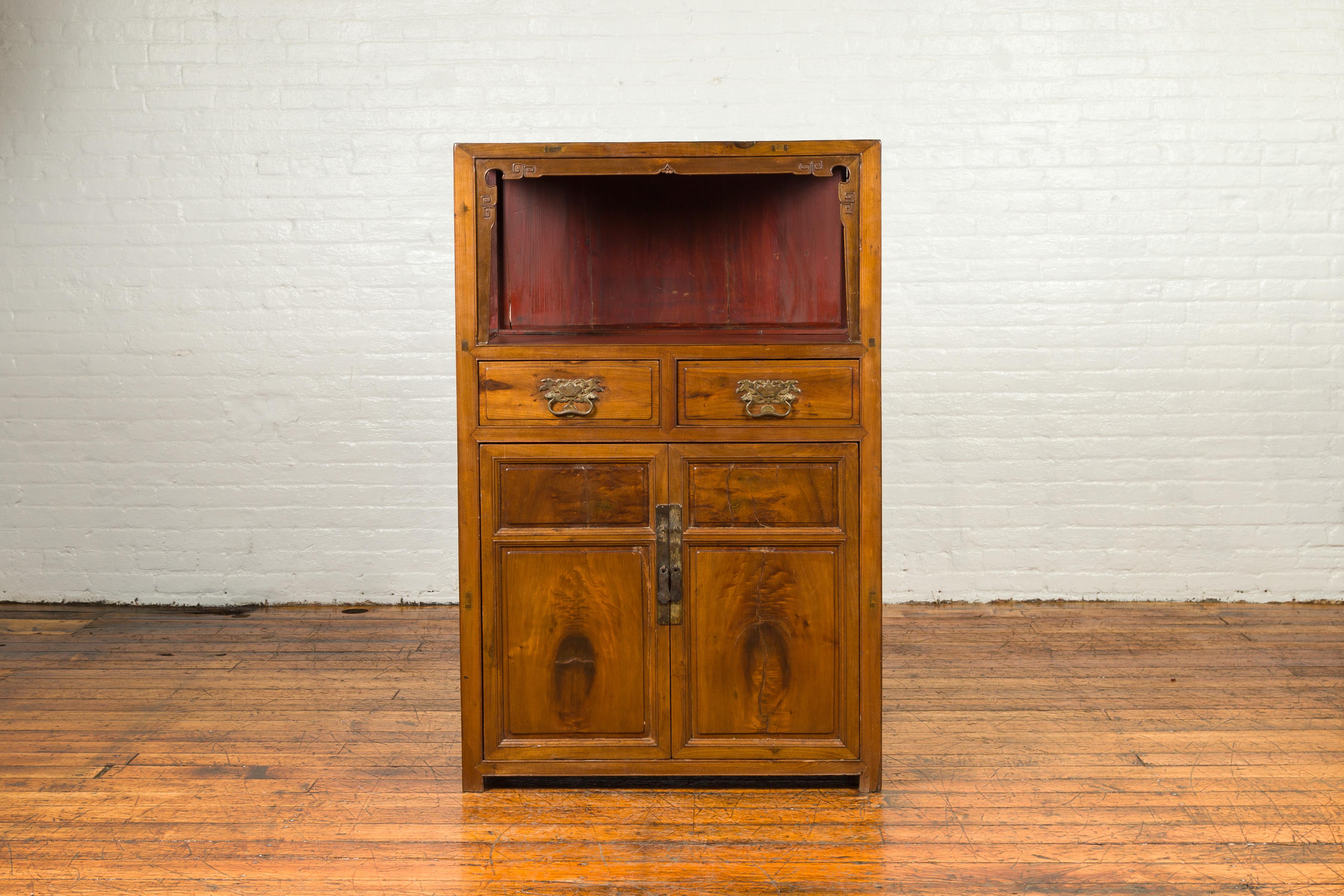 An antique Chinese Qing Dynasty period wooden bookcase from the 19th century, with open shelf, carved scrolls and two drawers over two doors. Crafted in China during the Qing Dynasty period, this bookcase features an open-shelved top with carved