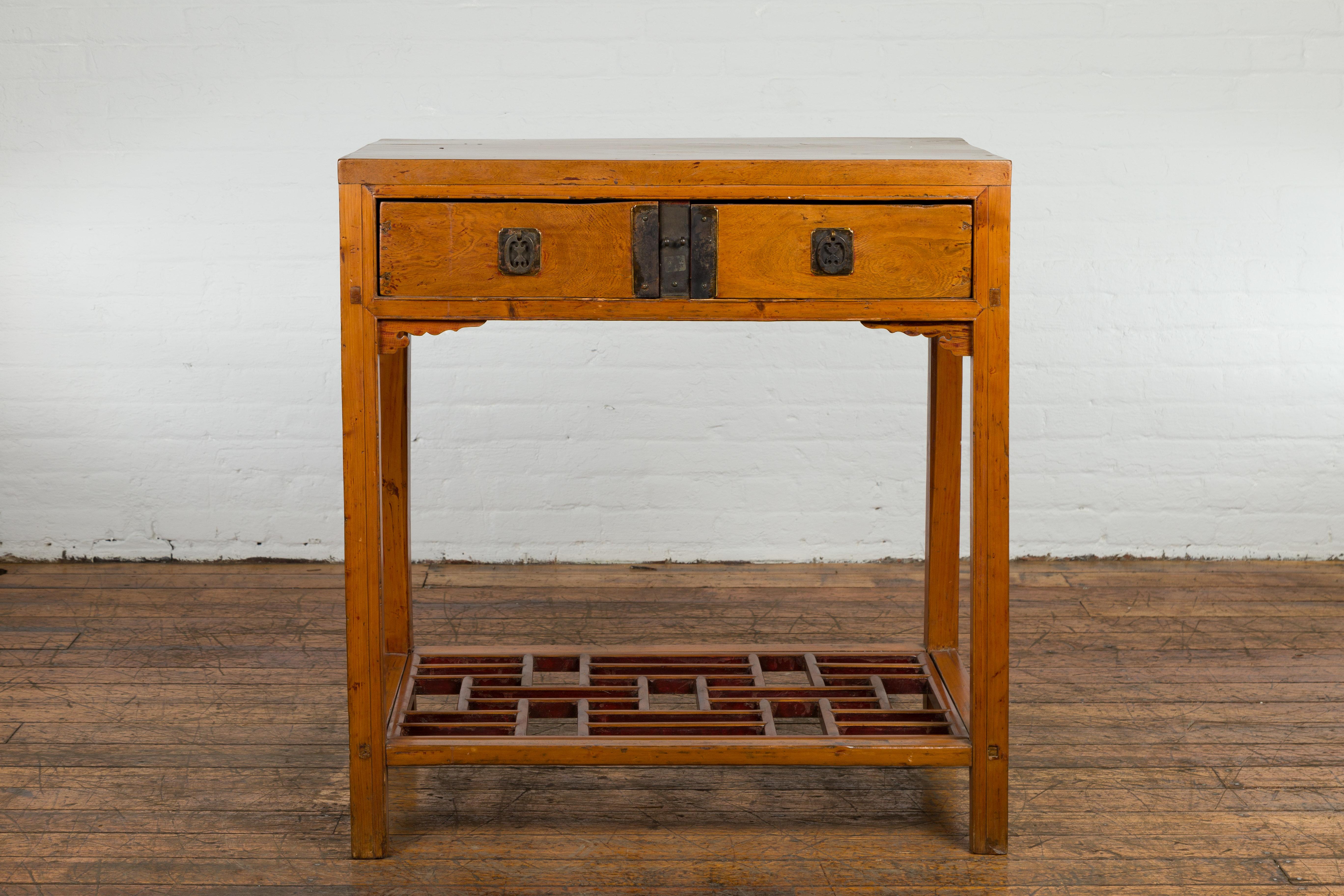 A Chinese Qing Dynasty period altar side console table from the 19th century with two drawers, fretwork shelf and bronze hardware. This 19th-century Qing Dynasty period altar side console table is an exquisite reflection of traditional Chinese