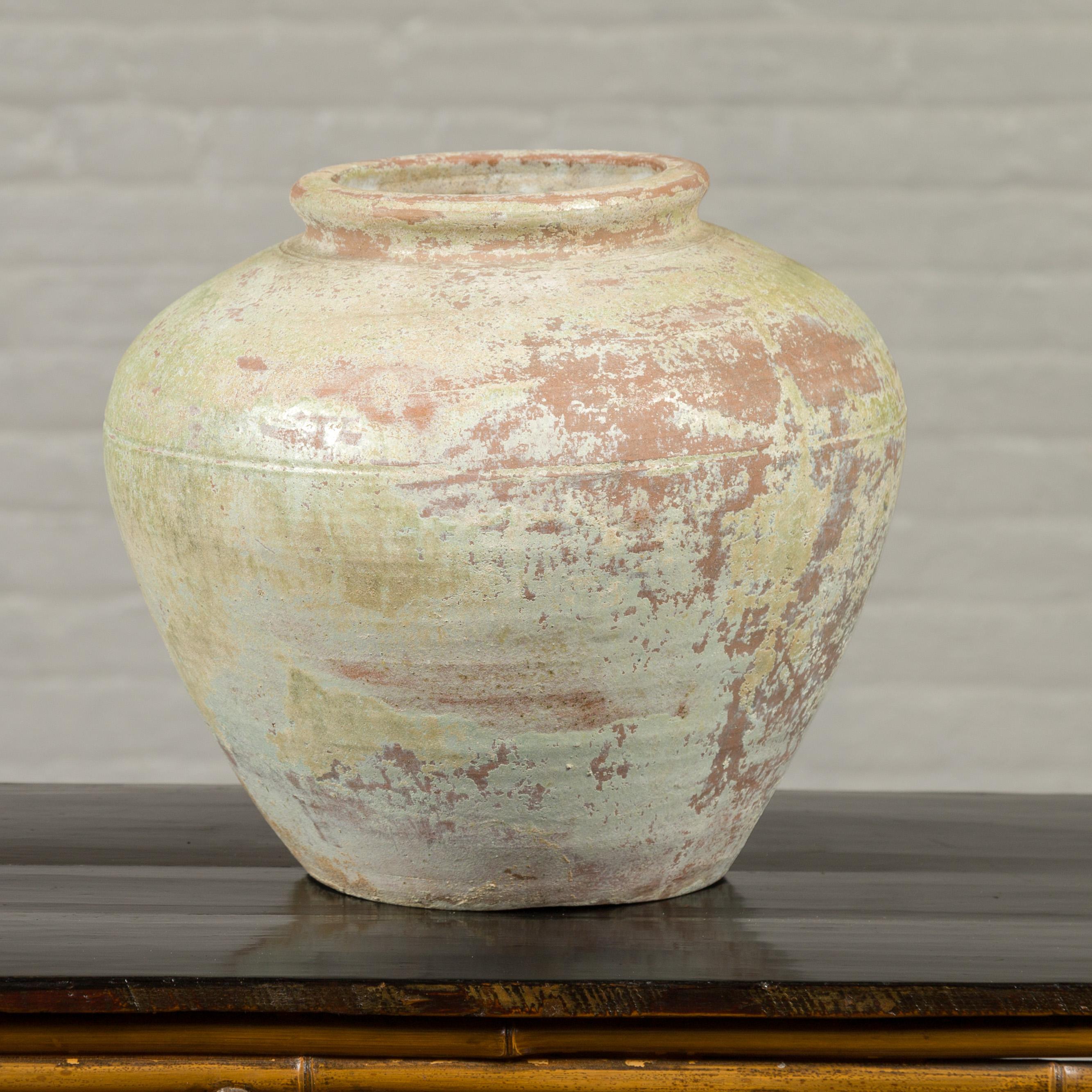 A Chinese Qing Dynasty period exterior vase from the 19th century with light yellow green glaze and weathered appearance. Crafted in China during the Qing Dynasty, this vase will make for an excellent garden ornament. Presenting a nicely weathered