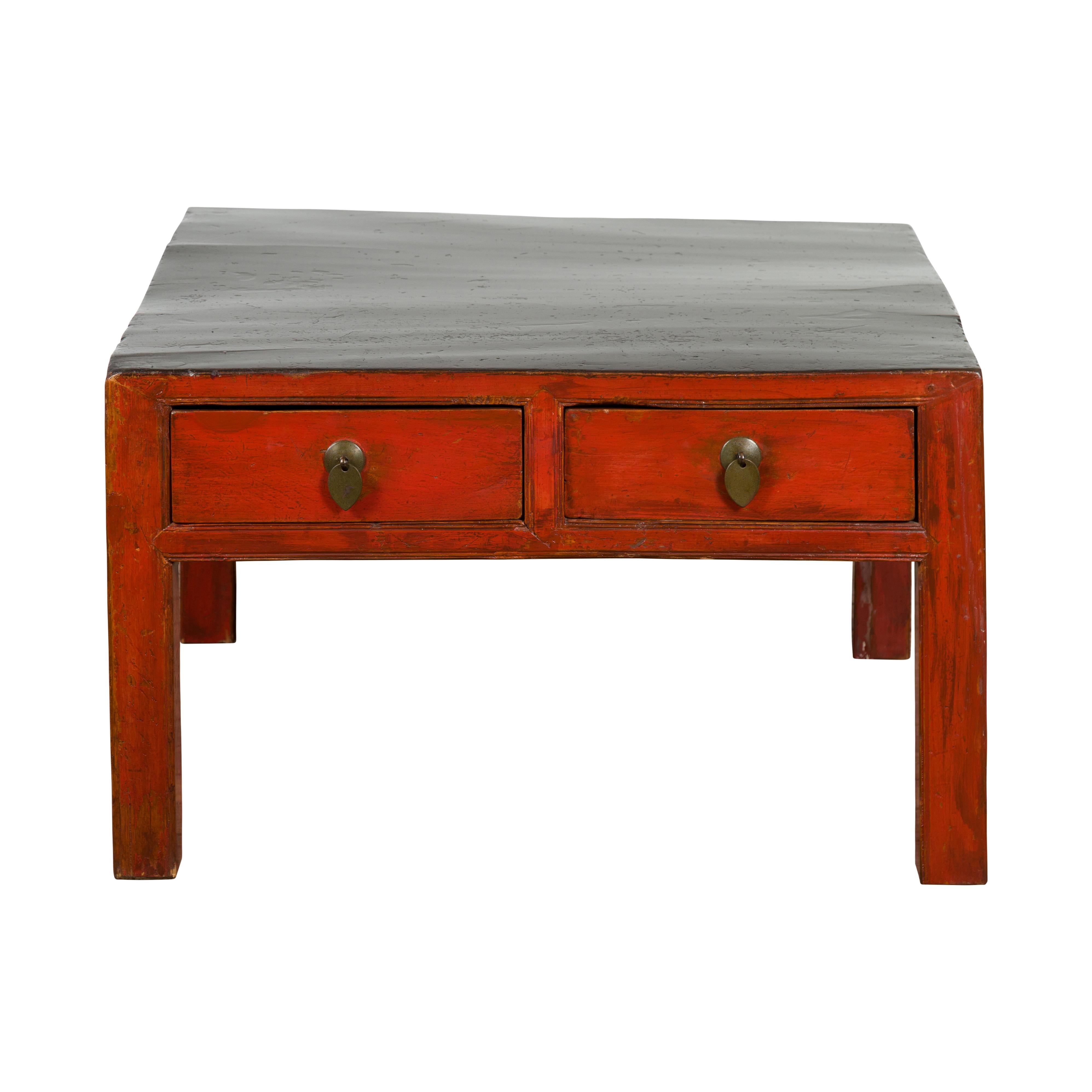 A Chinese Qing Dynasty period red and black lacquer coffee table from the 19th century, with four drawers, brass hardware and straight legs. Experience the timeless elegance of this Chinese Qing Dynasty period lacquer coffee table from the 19th
