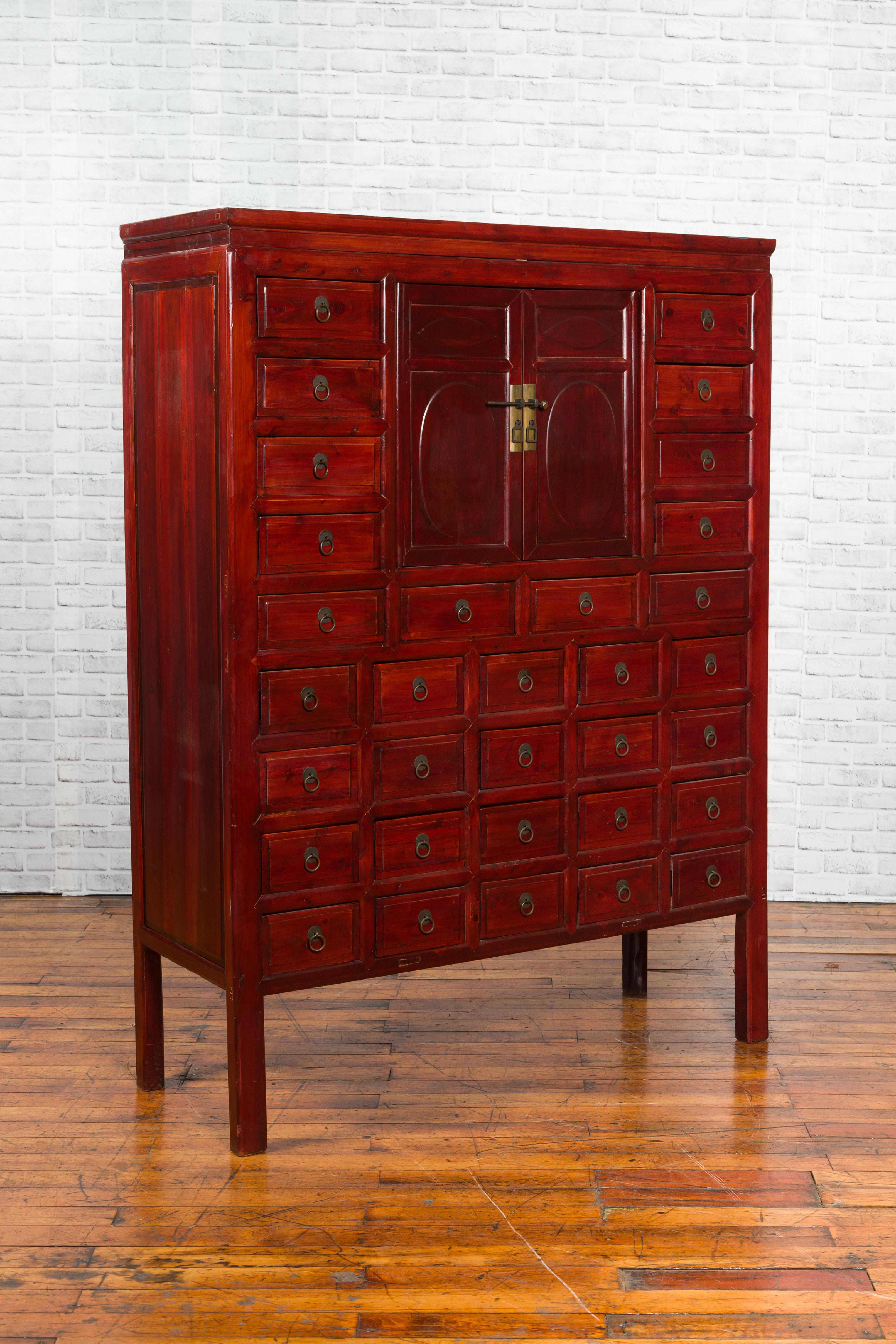 Chinois Armoire d'apothicaire chinoise des années 1930 en laque rouge avec 32 tiroirs et panneaux sculptés en vente