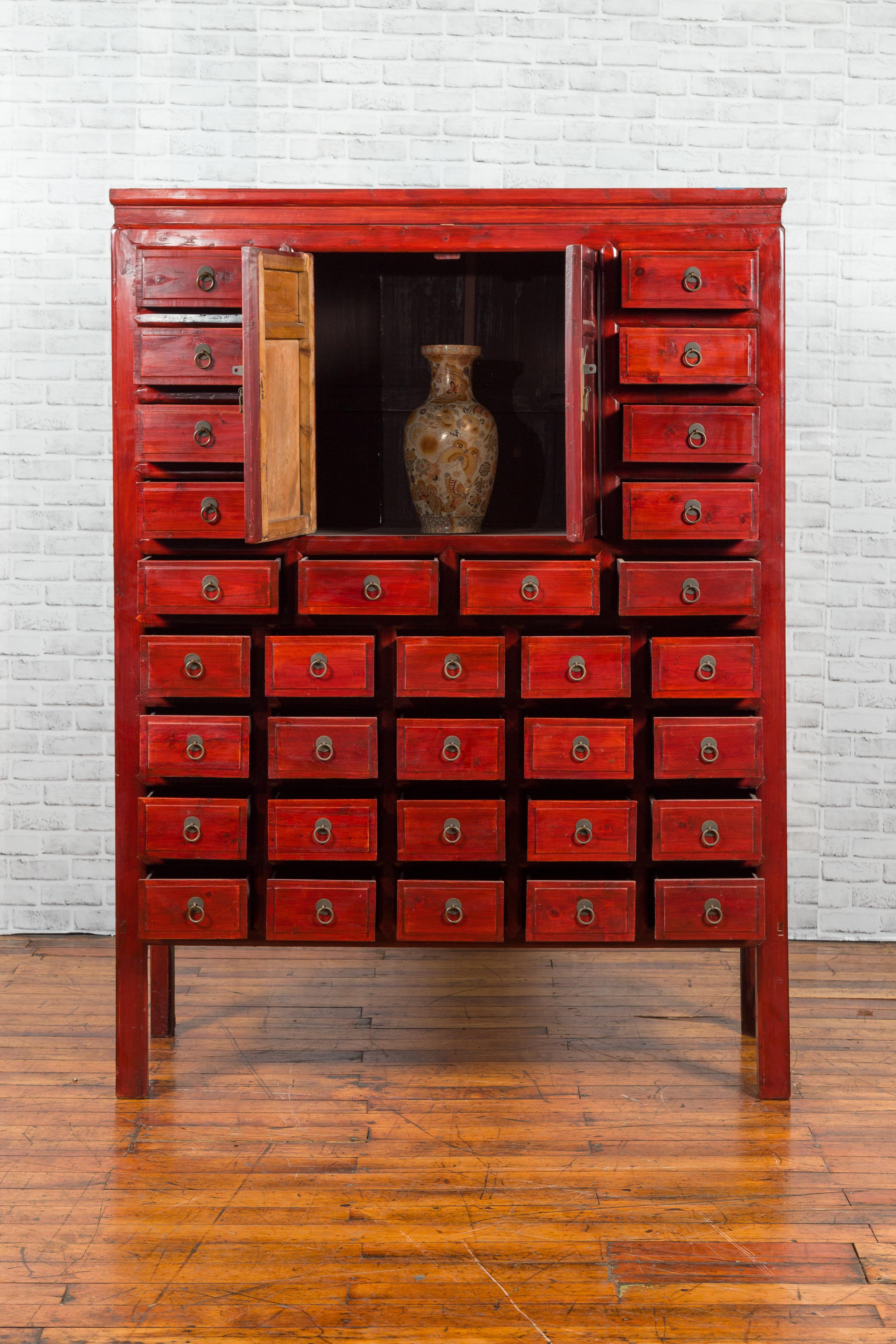 Laqué Armoire d'apothicaire chinoise des années 1930 en laque rouge avec 32 tiroirs et panneaux sculptés en vente