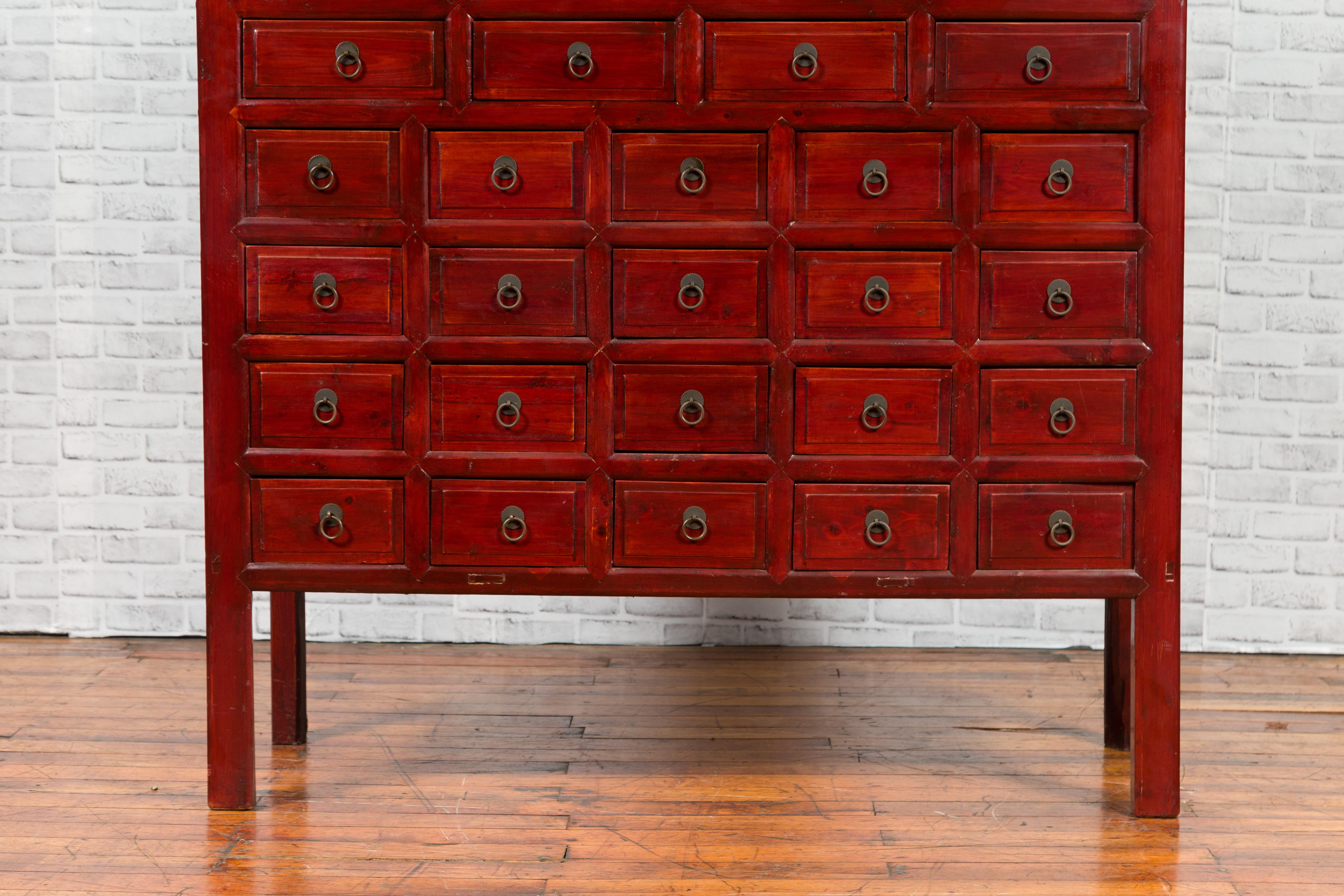 Bois Armoire d'apothicaire chinoise des années 1930 en laque rouge avec 32 tiroirs et panneaux sculptés en vente