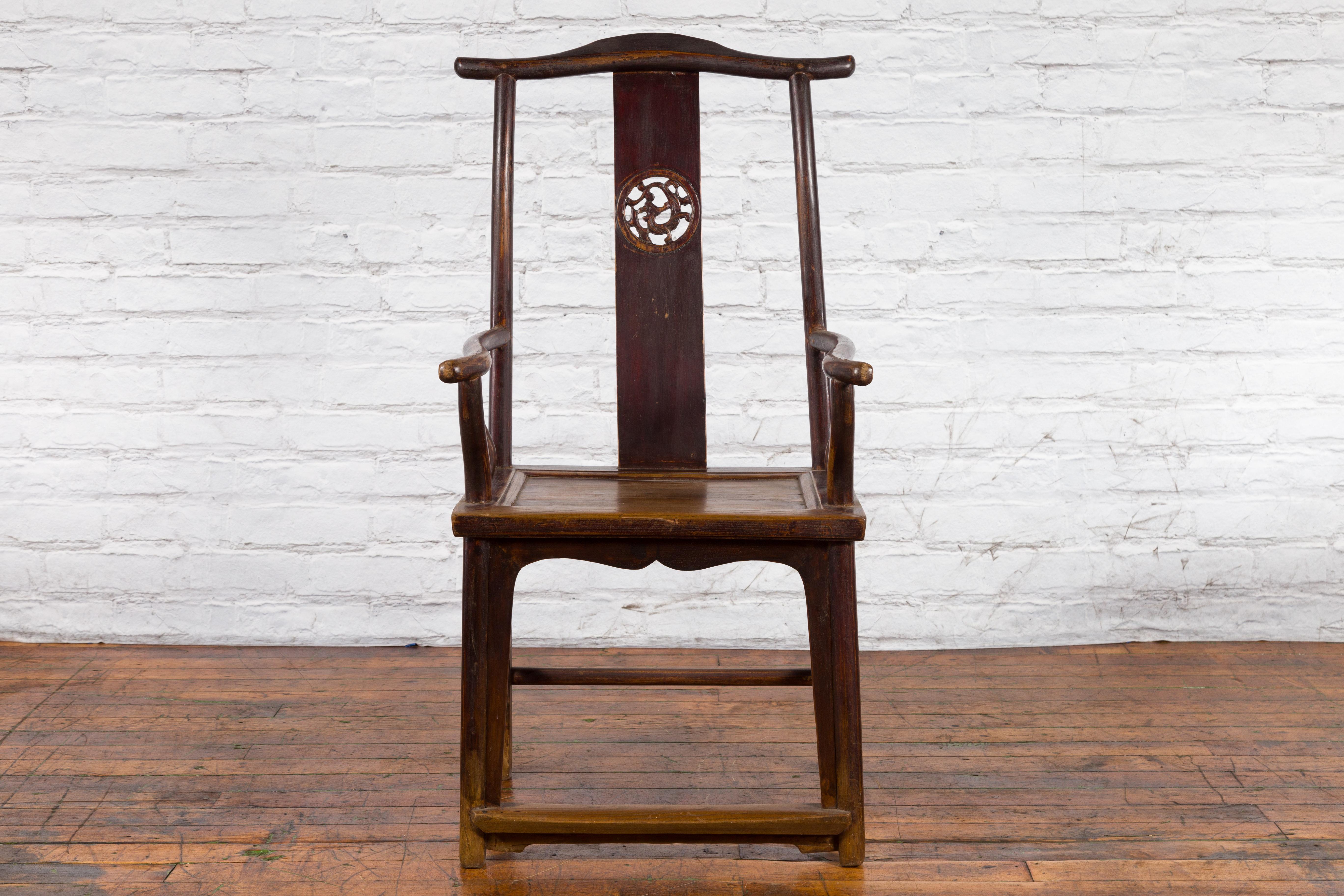 A Chinese Qing Dynasty period wooden scholar's lamp-hanger armchair from the 19th century, with carved splat, curving arms and brown patina. Created in China during the Qing dynasty, this scholar's lamp-hanger chair features an elegant tall back,