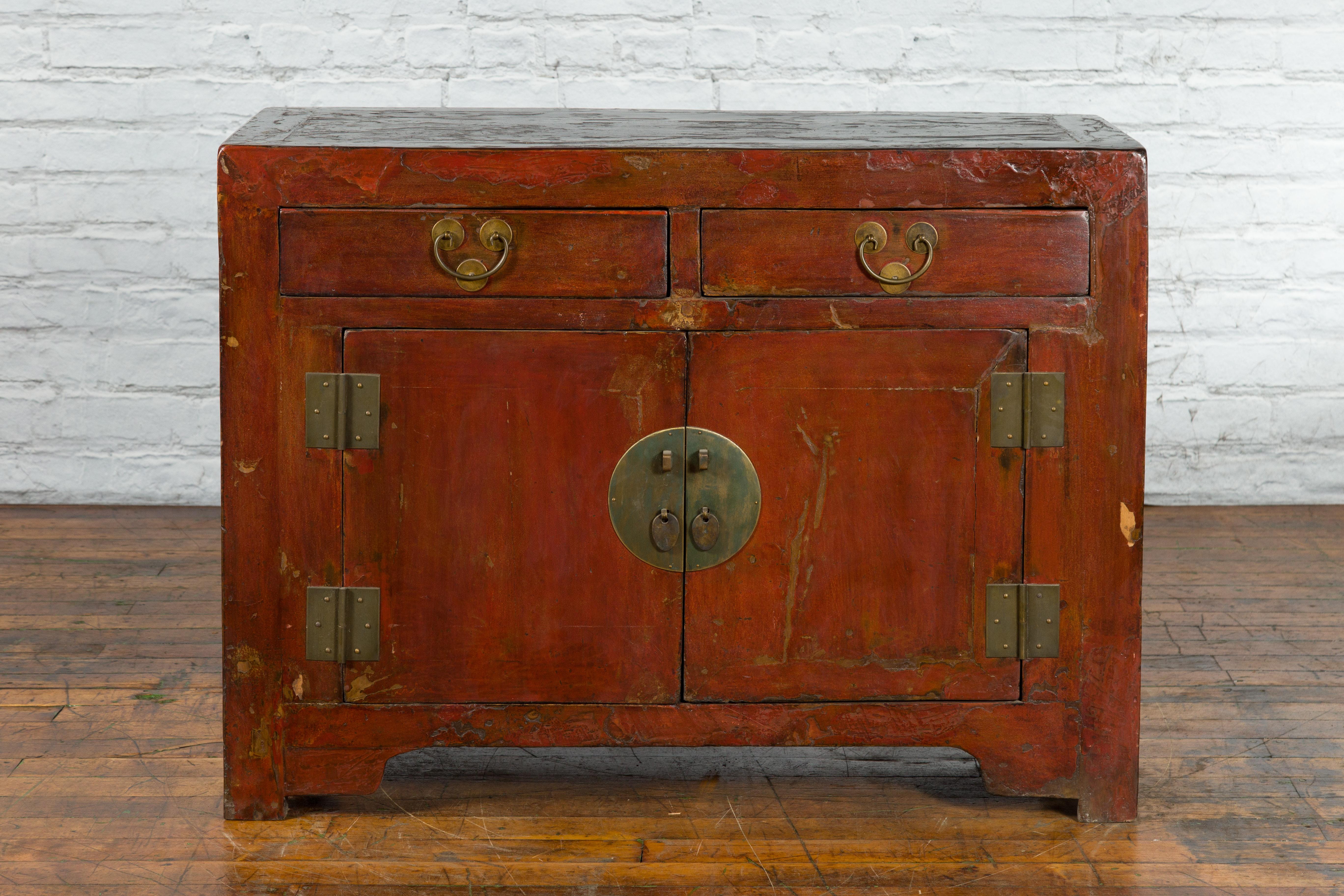 A Chinese Late Qing Dynasty period reddish brown lacquer side cabinet from the early 20th century with two drawers, two doors and brass hardware. Created in China during the Late Qing Dynasty period in the early 20th century, this side cabinet