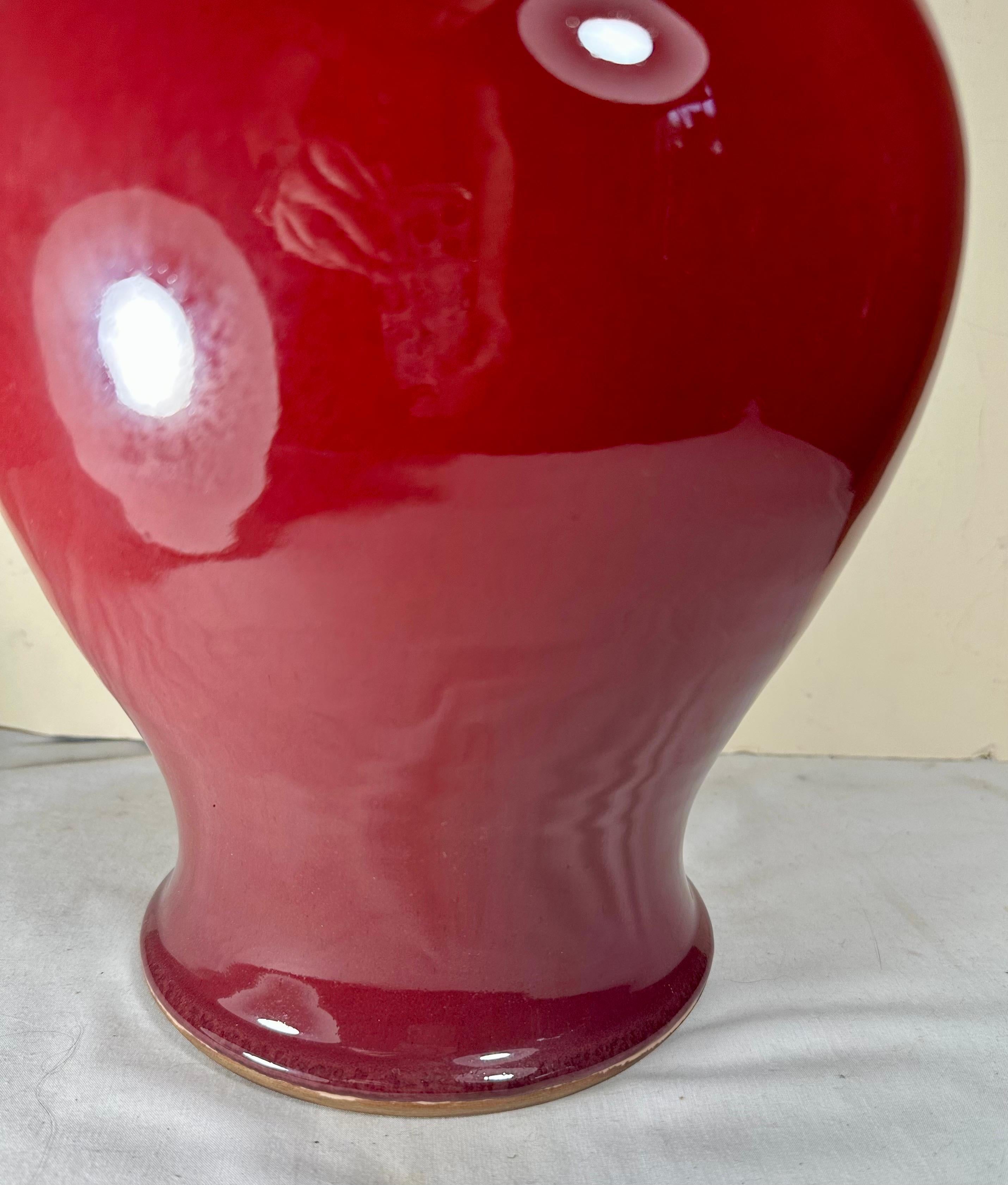 Magnifique vase en porcelaine chinoise monochrome de couleur sang de bœuf avec un corps robuste et arrondi et un long et élégant col évasé. Il a été créé dans la première moitié du 20e siècle. Les glaçures monochromes comme le sang de bœuf ont connu
