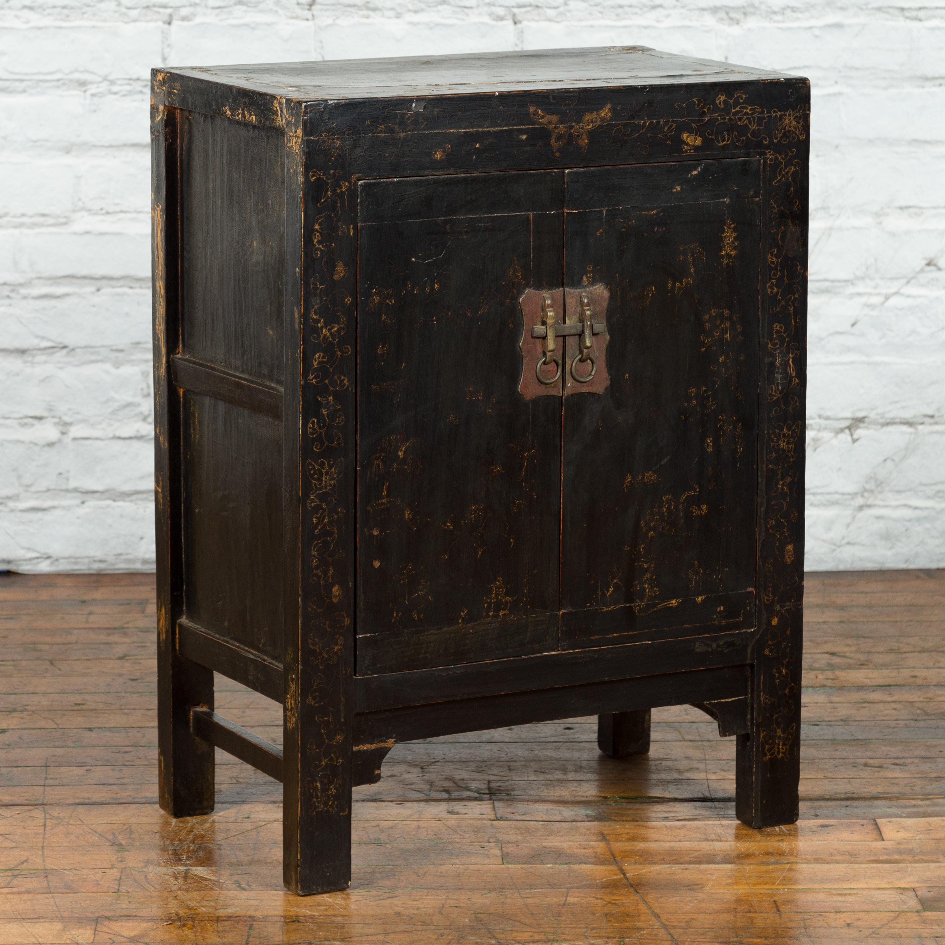 A Chinese Qing Dynasty period side cabinet from the 19th century, with original lacquer and faint painted décor. Created in China during the Qing Dynasty period, this side cabinet features a linear silhouette beautifully complimented by its original