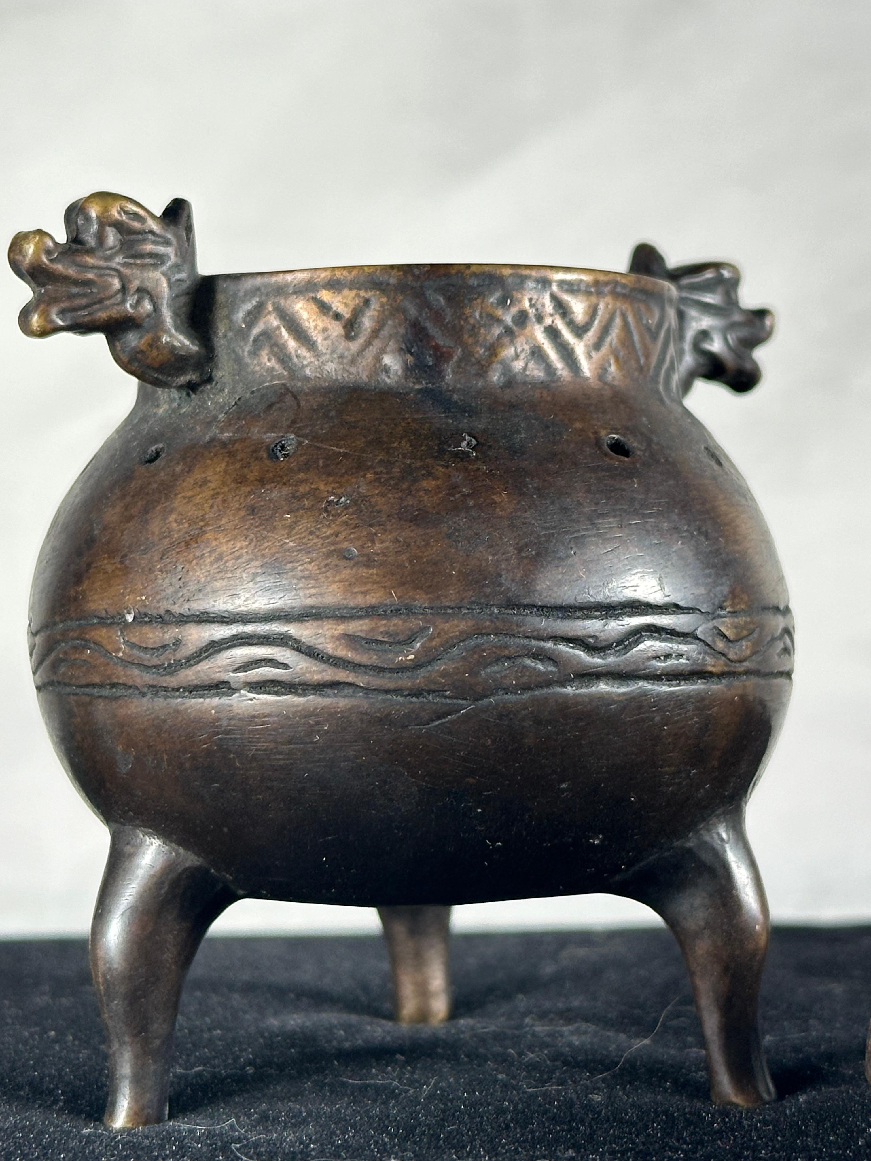 Chinese Qing Dynasty Small Bronze Tripod Censer

Small bronze censer from the Qing Dynasty 1644-1912, standing on three cabriole legs. Twin handles depict mythical creatures’ heads. The heavy body is pierced with small holes and is decorated with