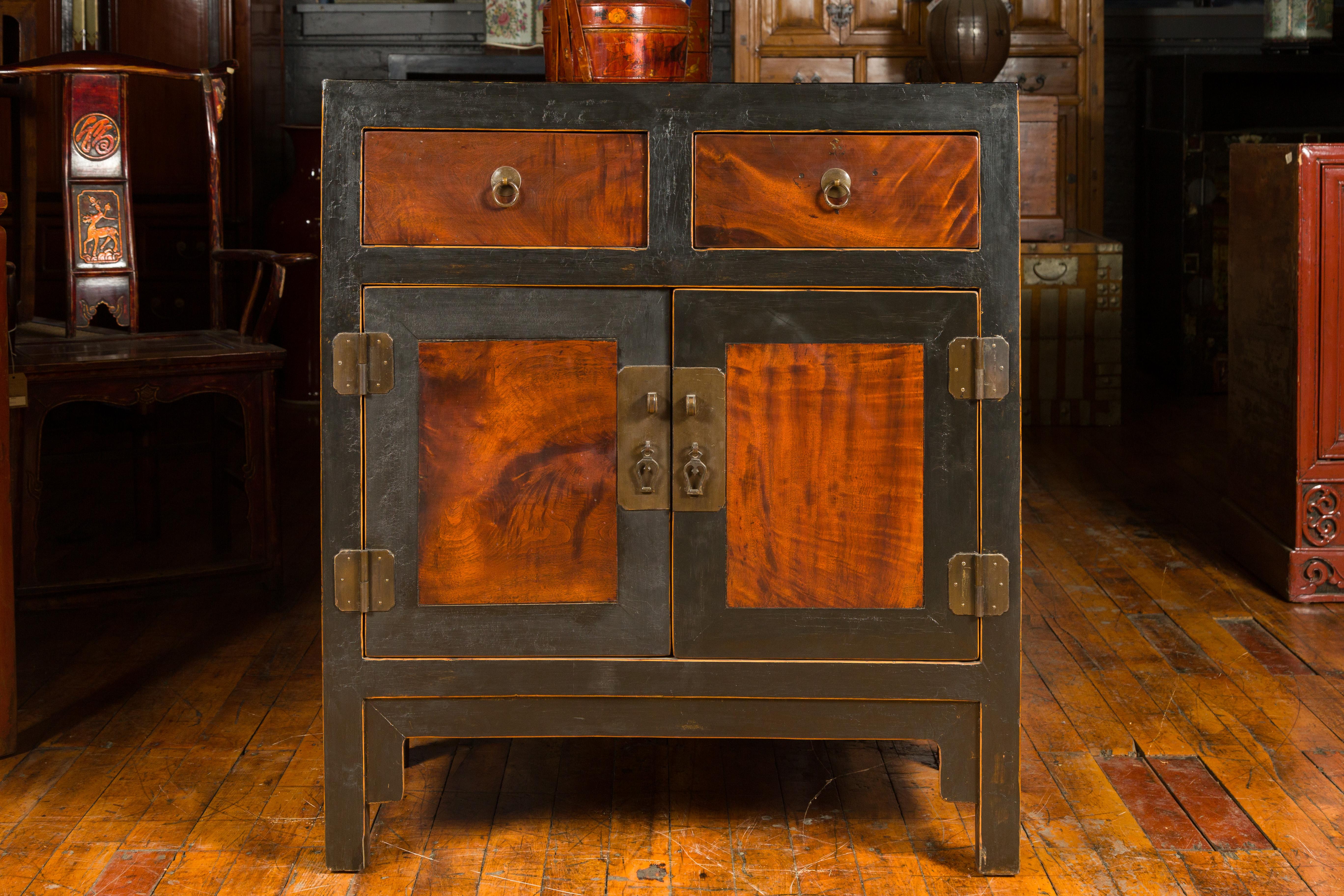 A Qing Dynasty period antique two-toned cabinet from the 19th century, with two drawers over double doors. This Qing Dynasty era antique cabinet, hailing from 19th-century China, presents a distinguished two-toned exterior that gracefully combines