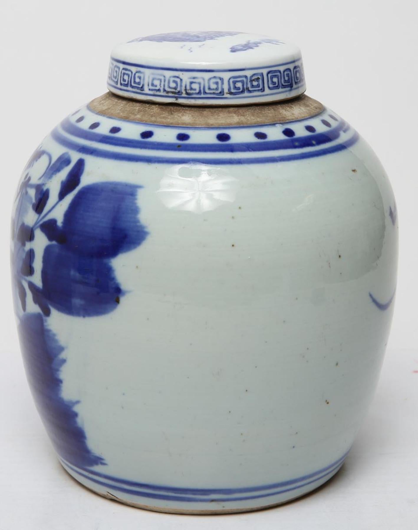 Chinese Qing dynasty ginger jar in underglaze blue and white porcelain, painted with lotus flowers, buds and pods; the lid with tiny landscape and Greek key border. In good vintage condition.