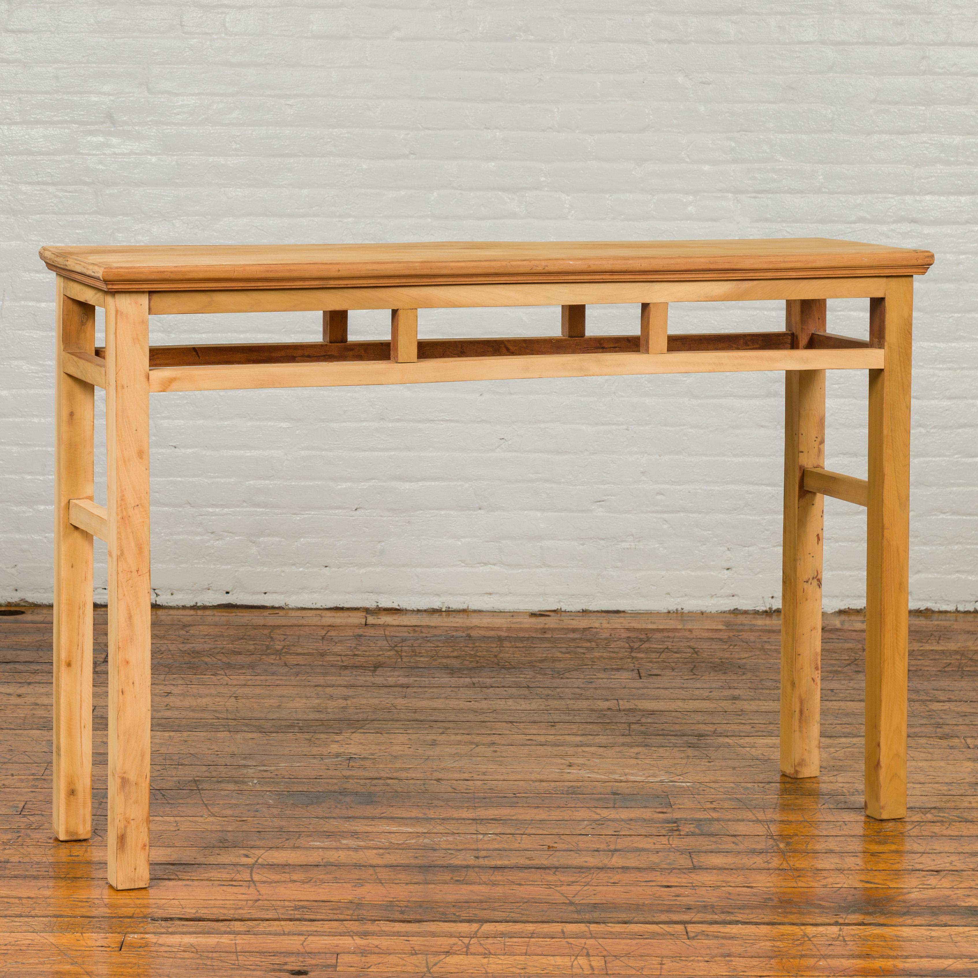 An antique Chinese Qing dynasty wooden console table from the early 20th century, with pillar-shaped strut motifs, straight legs and natural patina. Crafted in China during the early years of the 20th century, this Qing period console table features