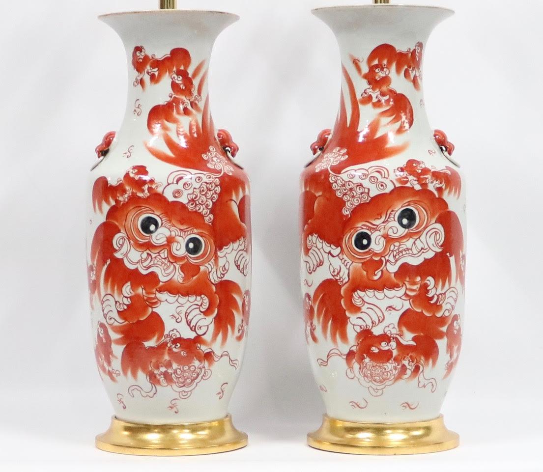 Chinese Qing dynasty pair of porcelain balusters vases mounted as table lamps, decorated with Classic iron red foo dogs / lions. Each vase has one large foo dog on the front of the vase surrounded by smaller ones. On the back side are rows of