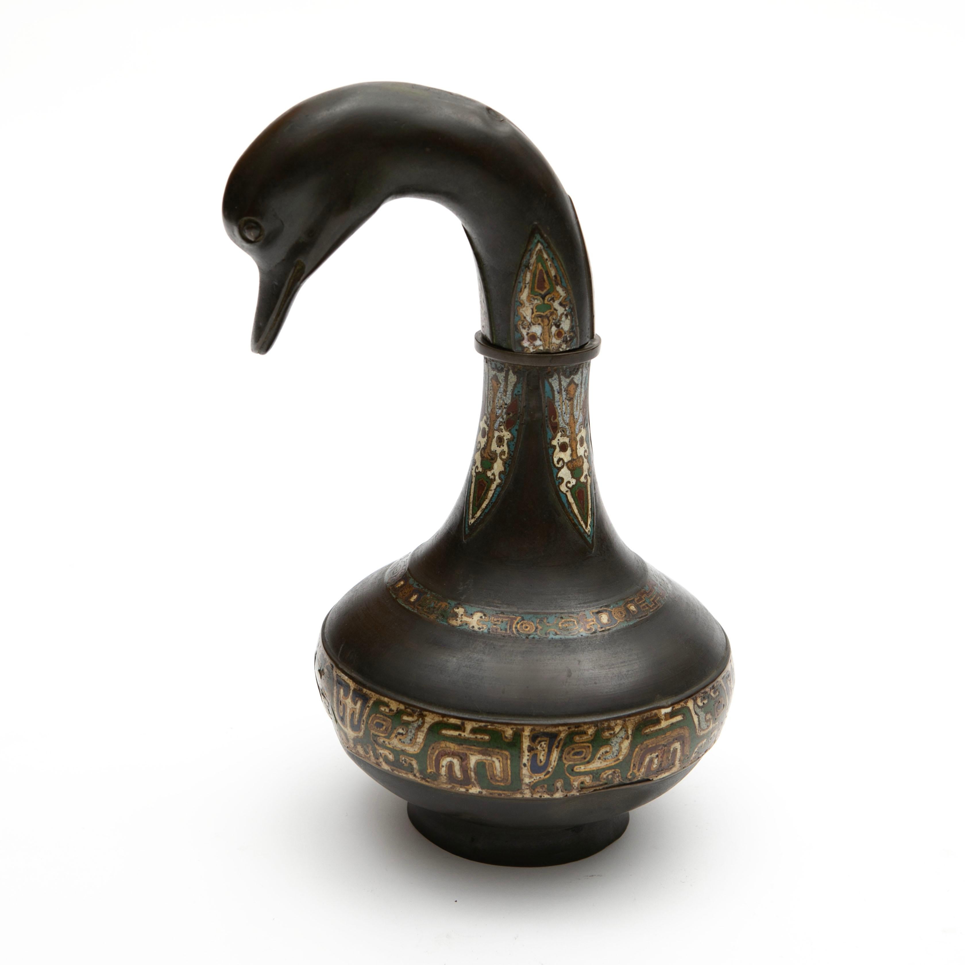 Vasija china para vino, de bronce patinado oscuro, en forma de elegante ganso con el cuello graciosamente curvado.
El aguamanil está adornado con un trabajo de cloisonné de gran calidad, con incrustaciones de esmalte en tonos verdes, azules, blancos