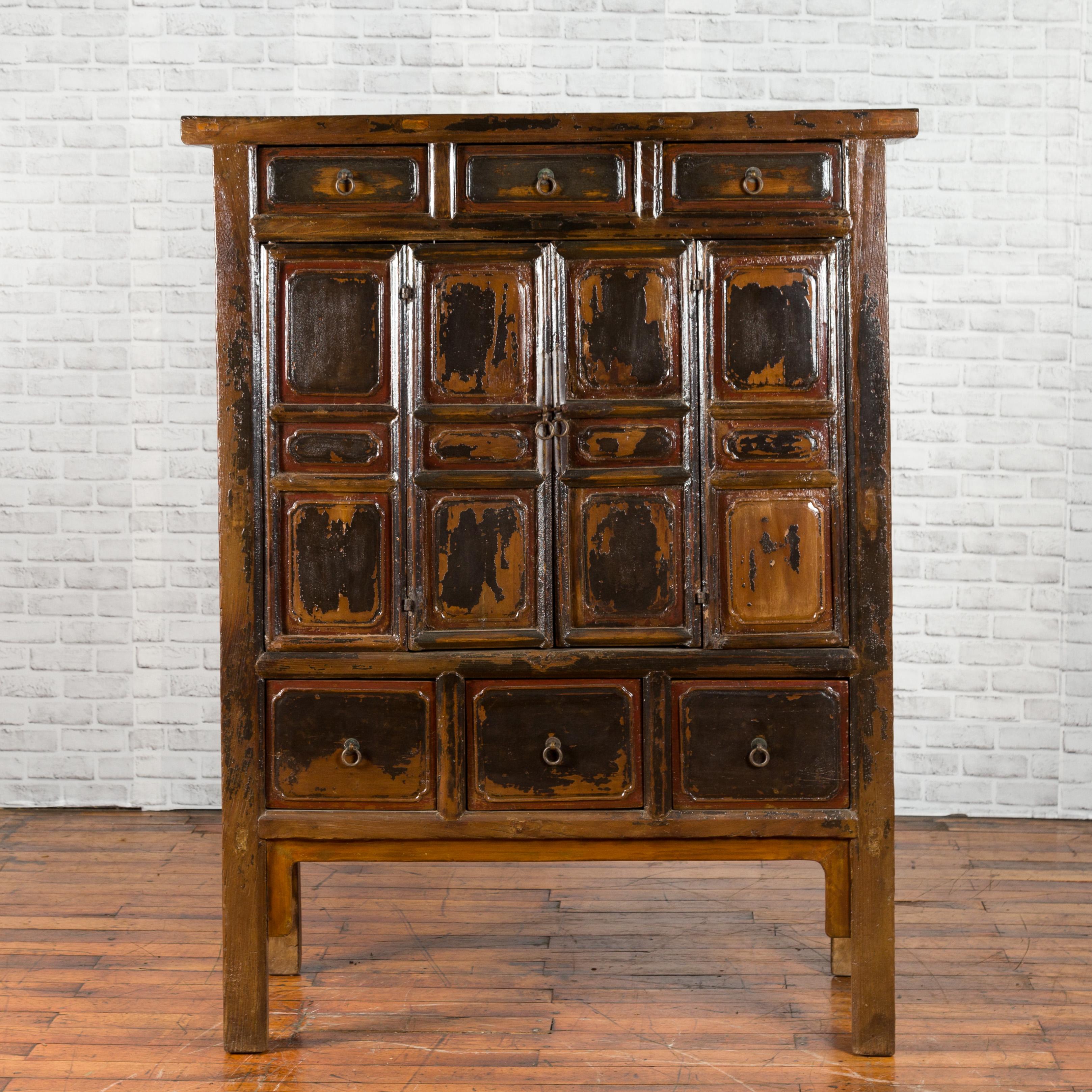 A Chinese Qing dynasty cabinet from the mid-19th century, with distressed patina, six drawers and folding doors. Created in China during the 1850s, this small cabinet features a simple cornice sitting above three drawers fitted with ring pulls. The