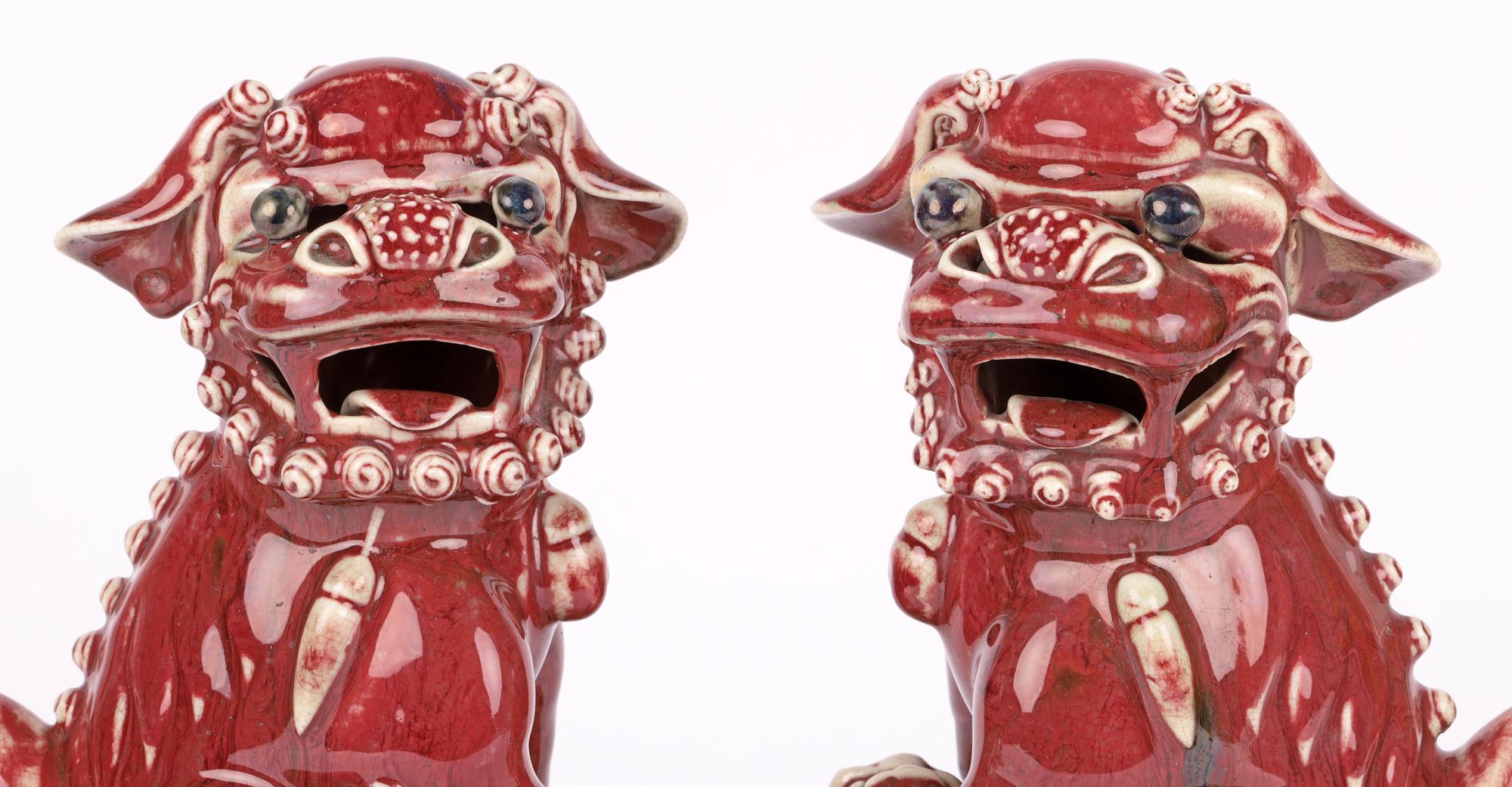 A rare and attractive pair Chinese Qing Jun-ware Foo dogs decorated in liver red glazes and dating from around 1850. The porcelain dogs are heavily made and stand raised on rectangular pierced hollow pedestal bases and stand looking sideways with