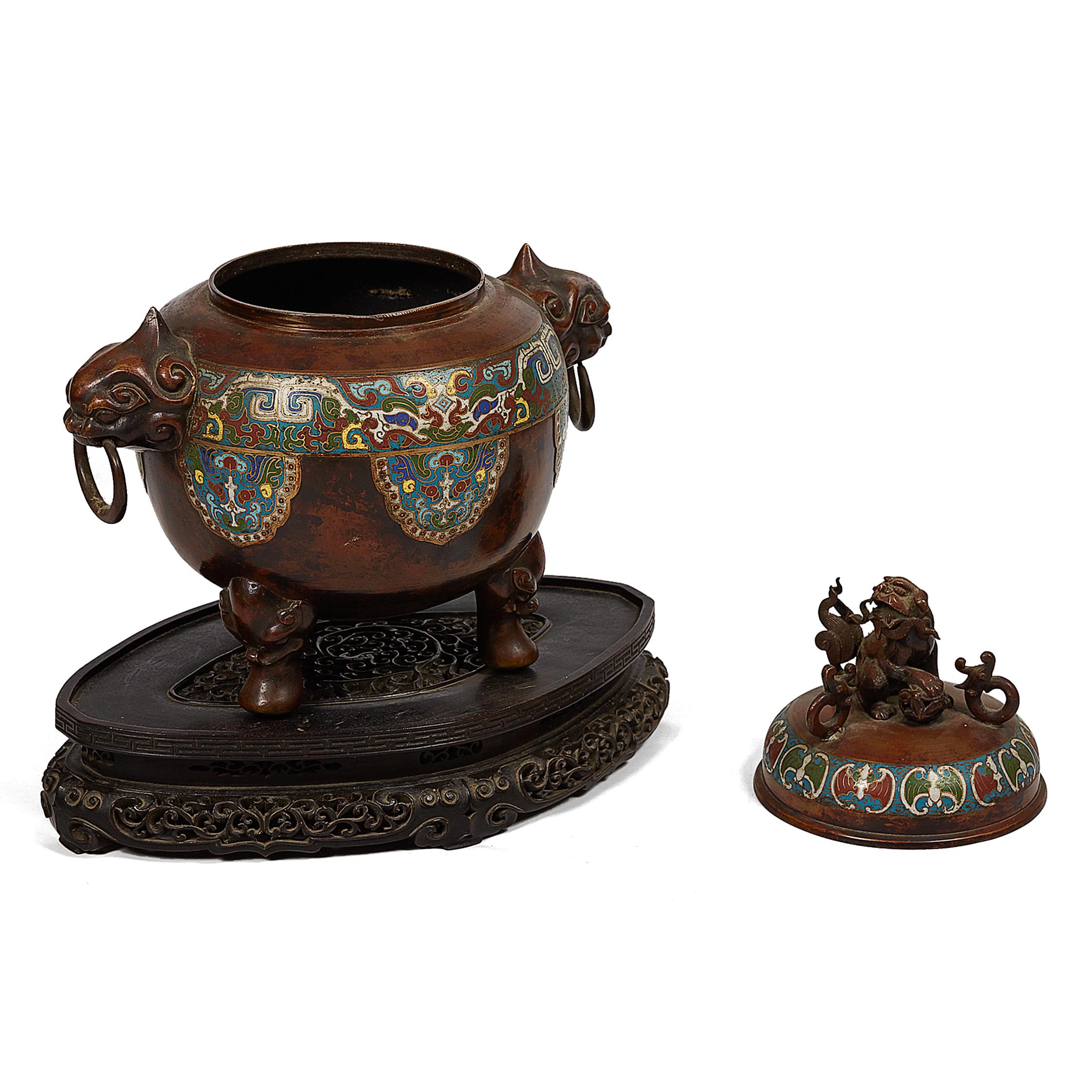 This Japanese censer incense burner, inspired by Chinese pieces, is of spheroidal form, the bronze body with polychrome champlevé enamel work flanked by dragon-head handles and ring pulls. The lid with a decorative polychrome champlevé enameled band