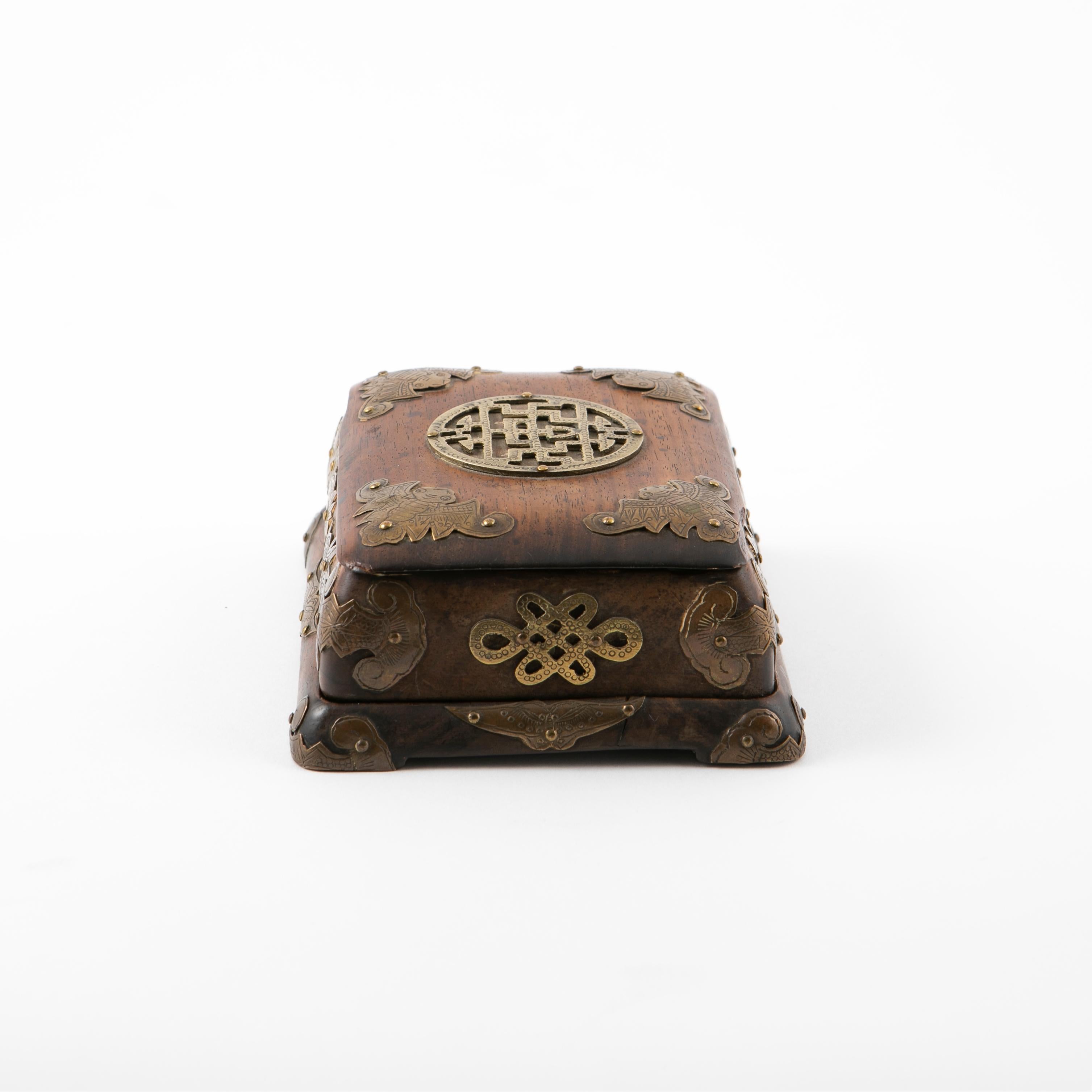 Chinese Huanghuali wood box decorated with bronze mountings and motifs of bats, fish and moths.
The top features a classic Chinese medallion mounted to the centre of the lid.
In untouched and original condition.

Minor chipping on the lid and on