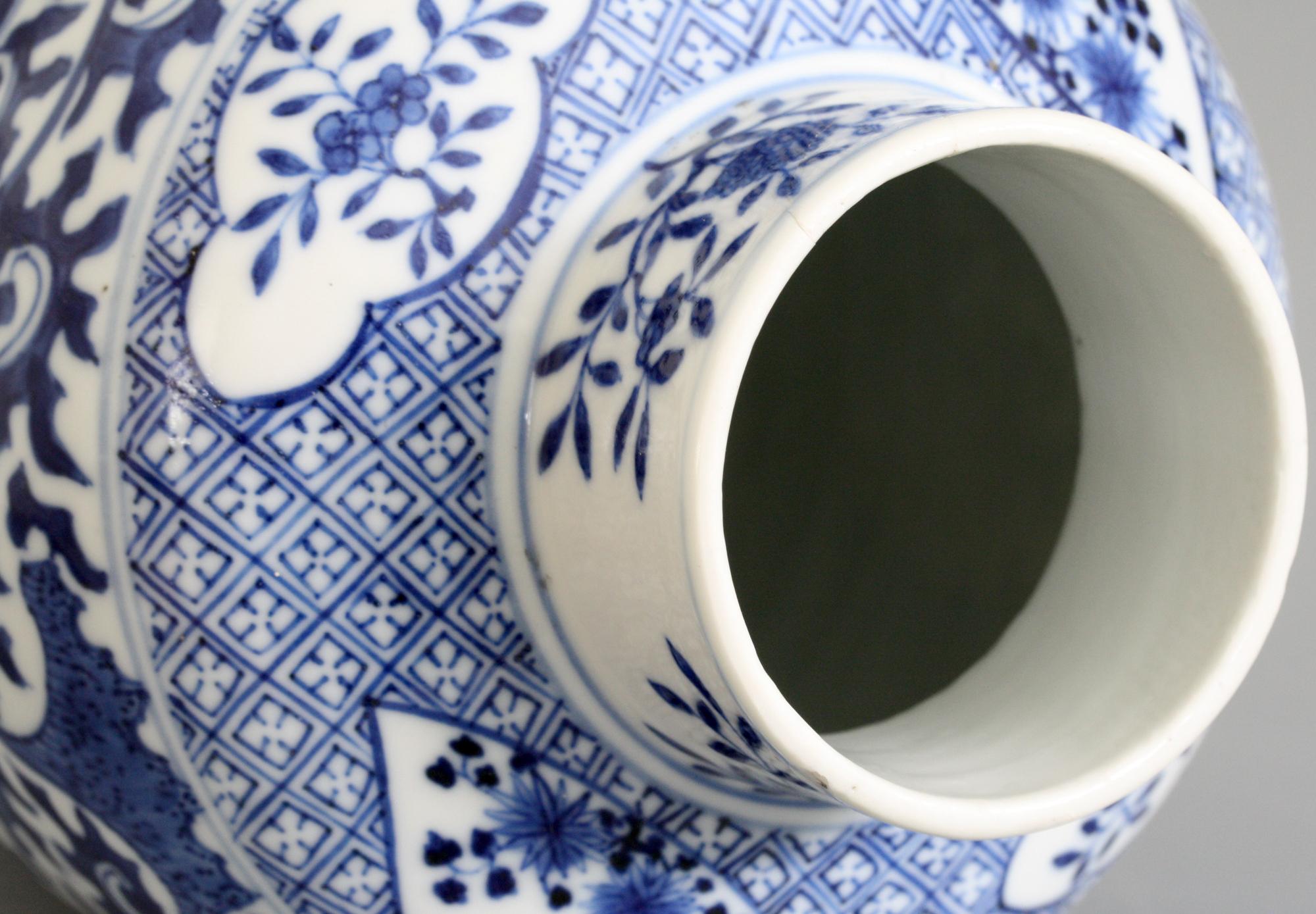 A tall antique Chinese Qing porcelain vase decorated in underglaze blue with scrolling lotus flower stems dating from the 19th century. The tall bulbous shaped vase stands on a wide rounded foot with a skirted rim and has a narrow funnel shaped top.