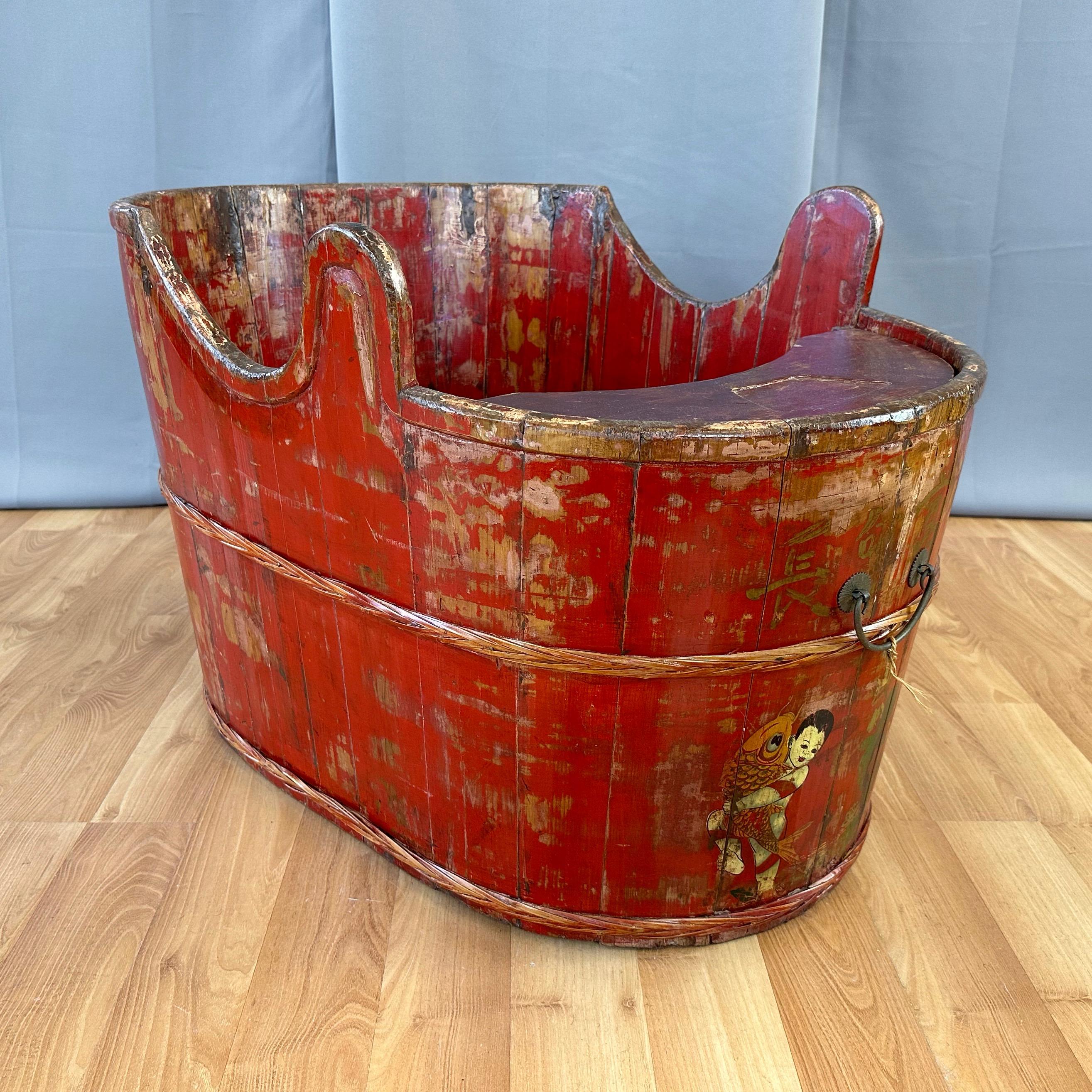 A delightful circa 1900 Qing era Chinese red lacquered wood child’s convertible combination bathtub and seat.

Oval staved wood plank body finished in brilliant red lacquer and a clear coat. With a higher back then front, and horn-like elements on