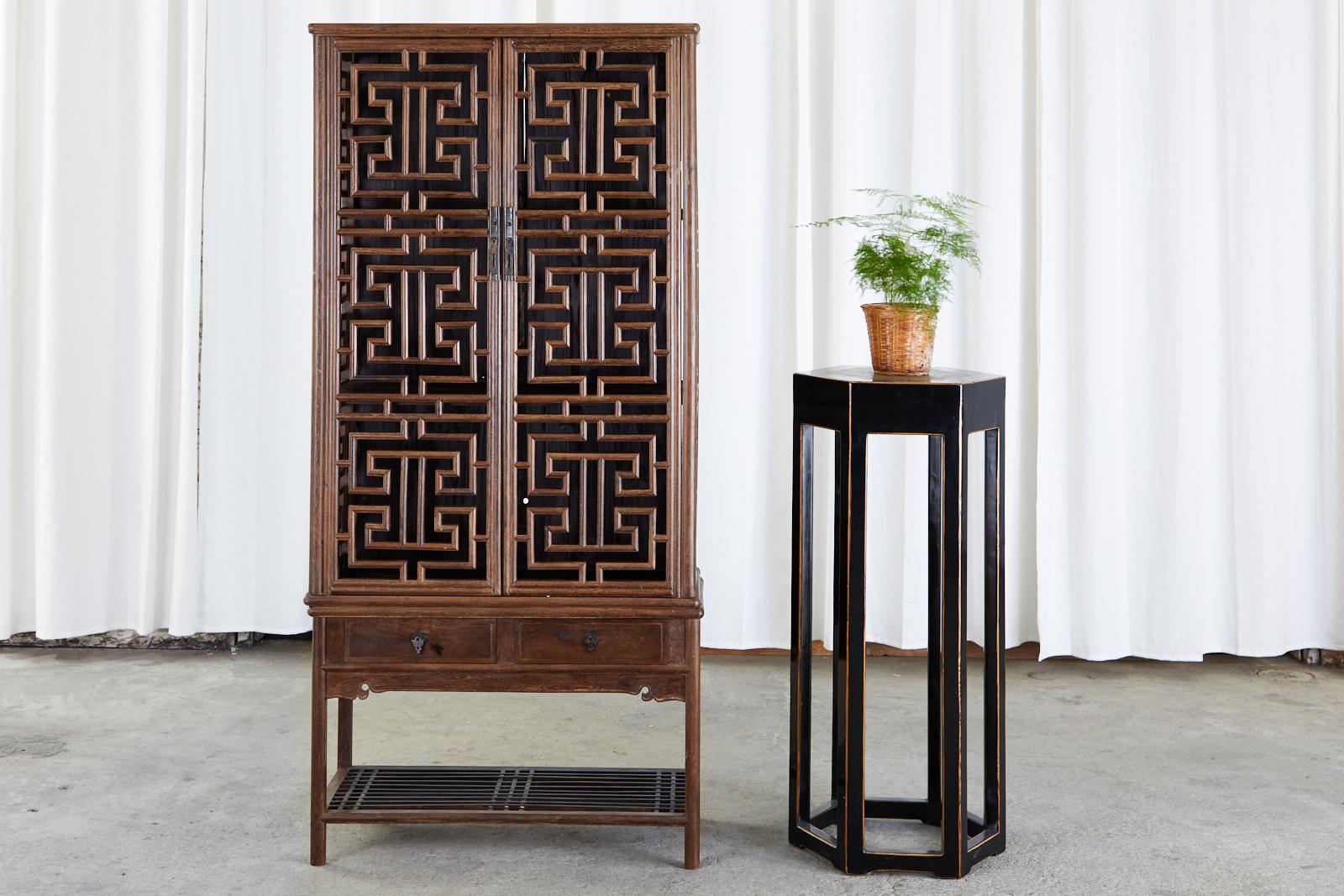Magnífico mueble de cocina chino de dos piezas, con una vitrina calada abierta de celosía tallada. Fabricada en estilo Qing con madera noble bellamente veteada. El armario superior de la cocina tiene dos puertas con tiradores de latón que se abren a