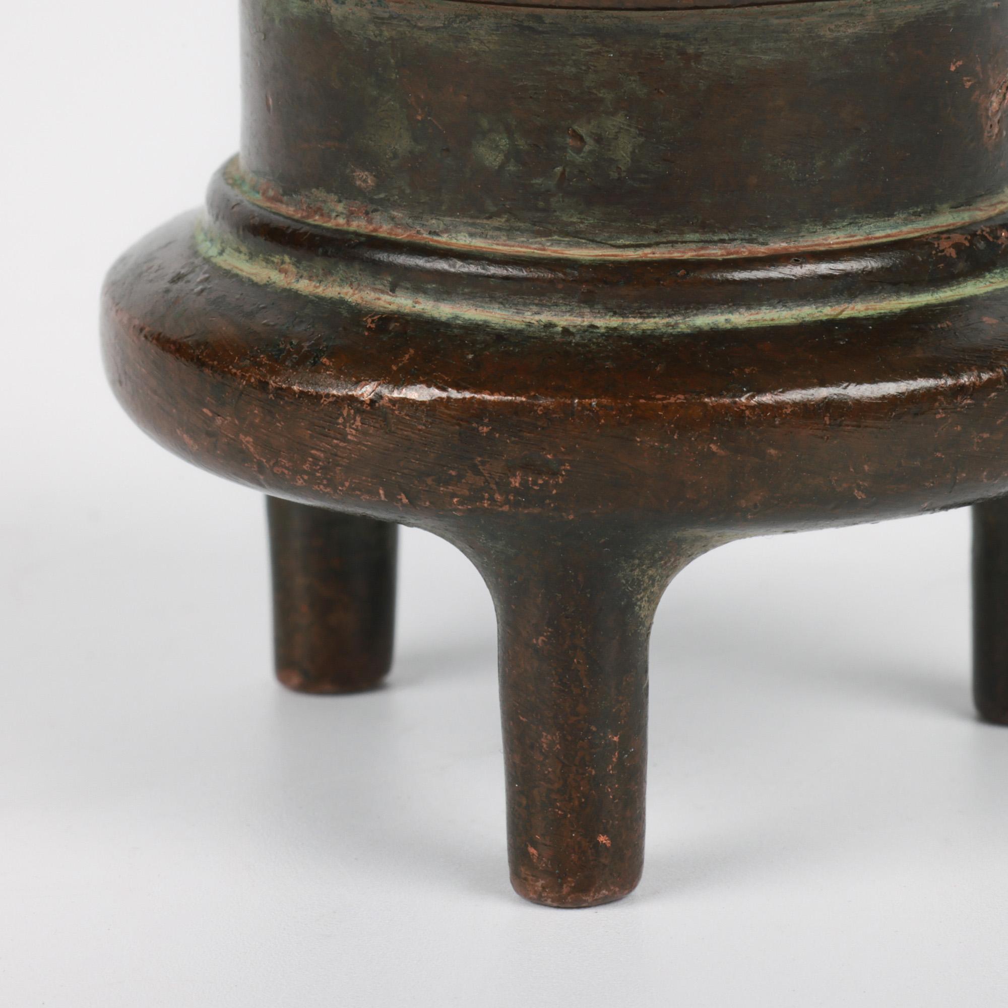 Antico incensiere cinese Qing (1644-1911) a due manici in bronzo a tripode, elegante e di ottima fattura, risalente al 18/19° secolo. L'incensiere poggia su tre gambe dalla forma semplice che sostengono un corpo a forma di calderone con un'ampia