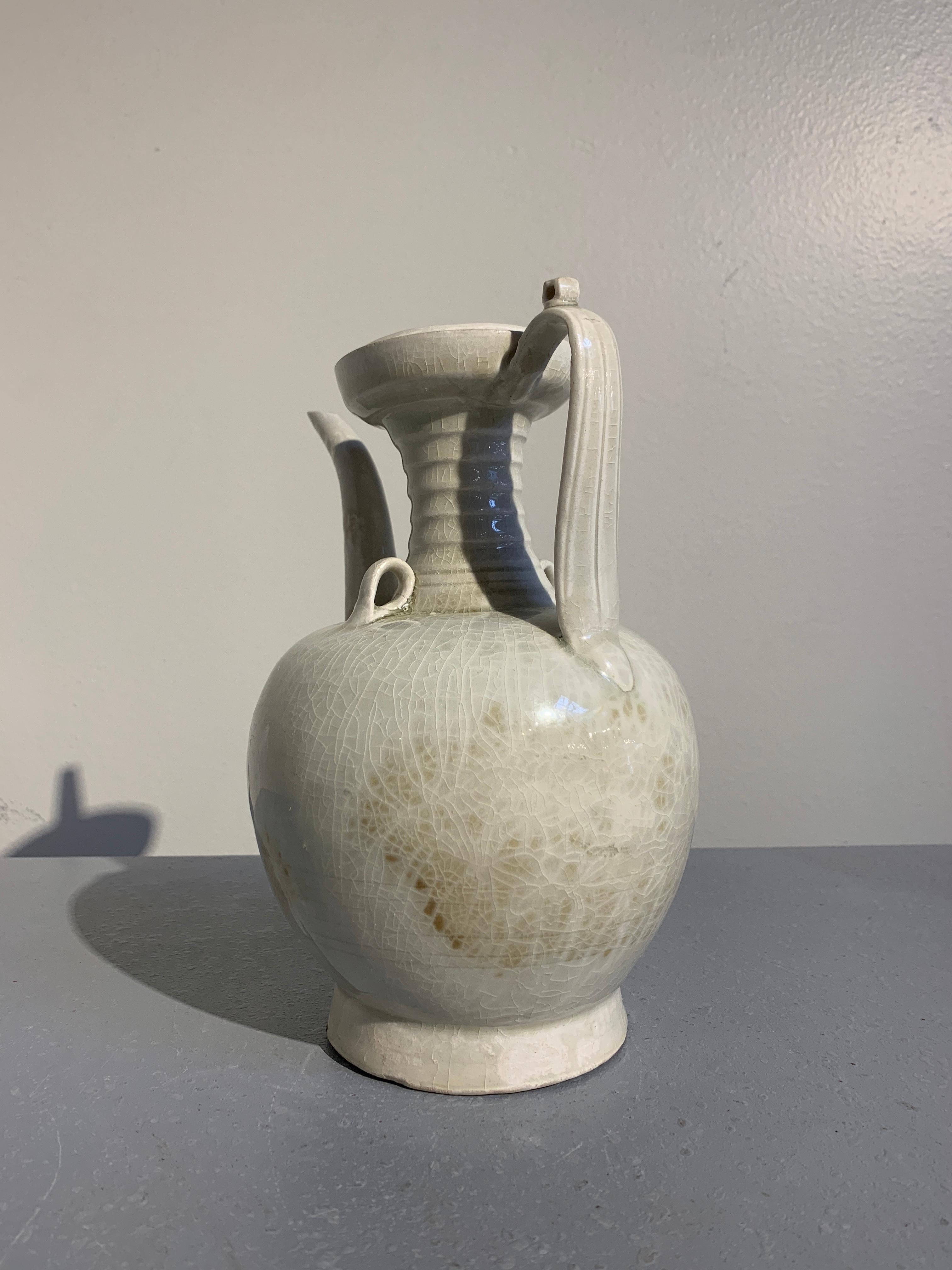 An elegant Chinese ewer with an attractive qingbai (yingqing) glaze, song Dynasty, early 13th century.

The ewer features a bulbous body resting on a tall, slightly splayed foot. The cup mouth supported by a tall, waisted neck with a bowstring