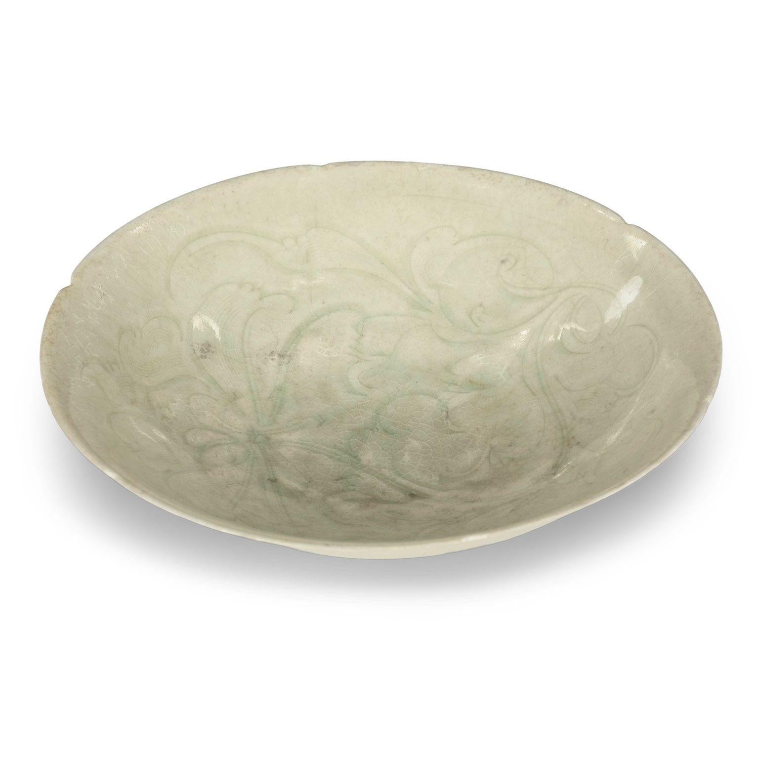 Chinese Qingbai lobed foliate-rim bowl, Song Dynasty, porcelain shallow bowl resting upon tapered footed base. Peony flower decoration incised upon interior of bowl. Known colloquially as celadon-jade, it is neither, but instead a type of Ding-ware