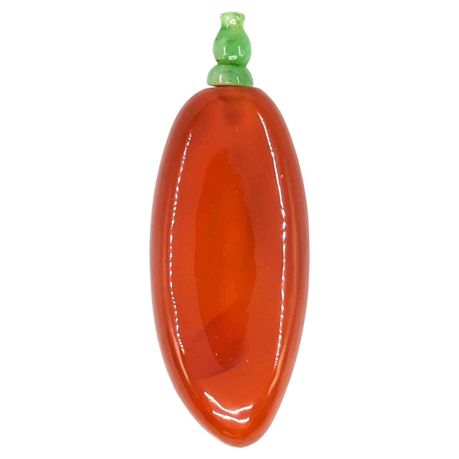 An antique Chinese carved agate snuff bottle with a carved green jadeite stopper. The intense red agate material shows real life likeness of a red pepper in shape and color, and is well accented with a hulu double gourd shaped jadeite stopper and