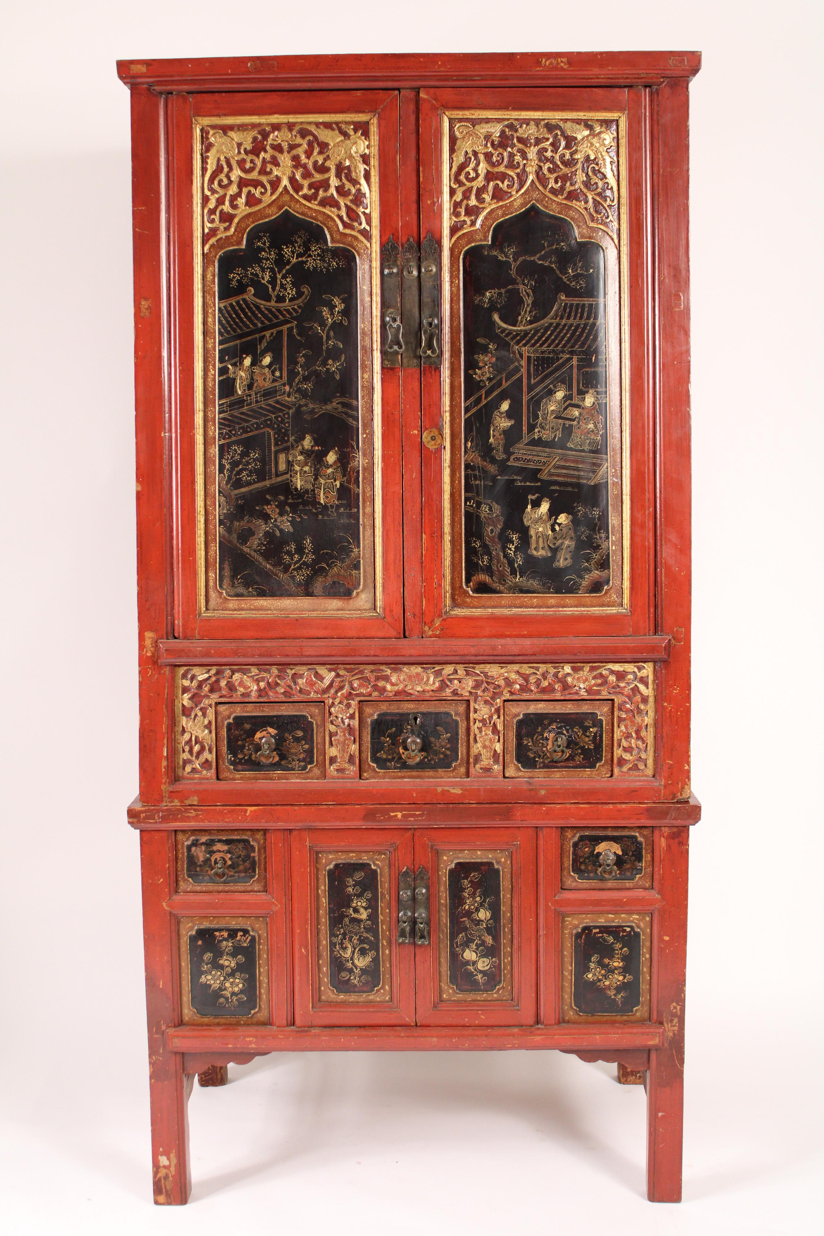 Chinese red, black and gilt chinoiserie decorated cabinet, circa mid 20th century. The upper black lacquer doors with Chinese figures in tea houses, the bottom black lacquer drawers and doors with floral designs. The cabinet having two upper doors,