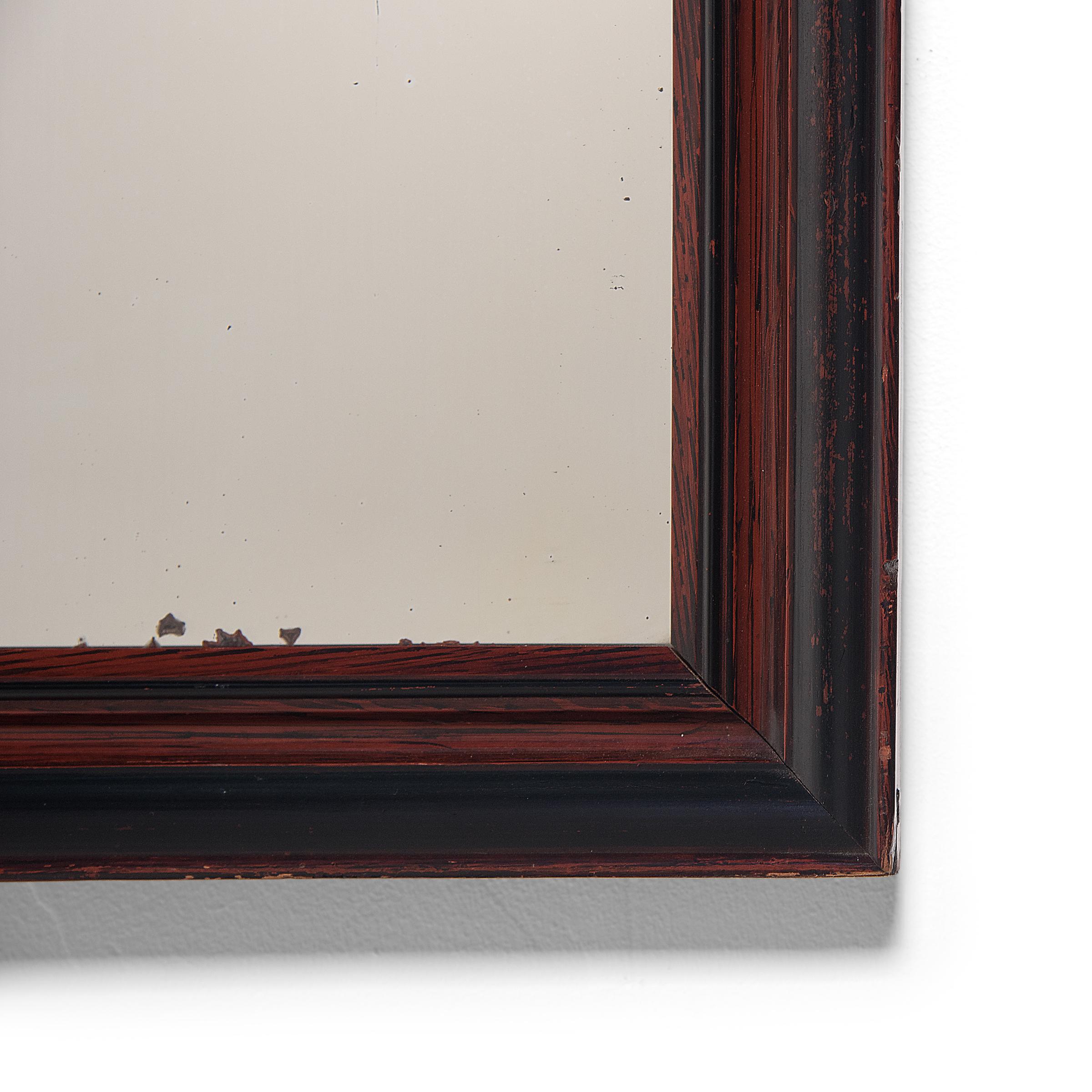 This charming wall mirror was crafted in China's Guangdong province and dates to the early 20th century. The rectangular frame is colored with finely brushed red and black lacquer, for a rustic finish. The mitered frame encloses the original mirror,