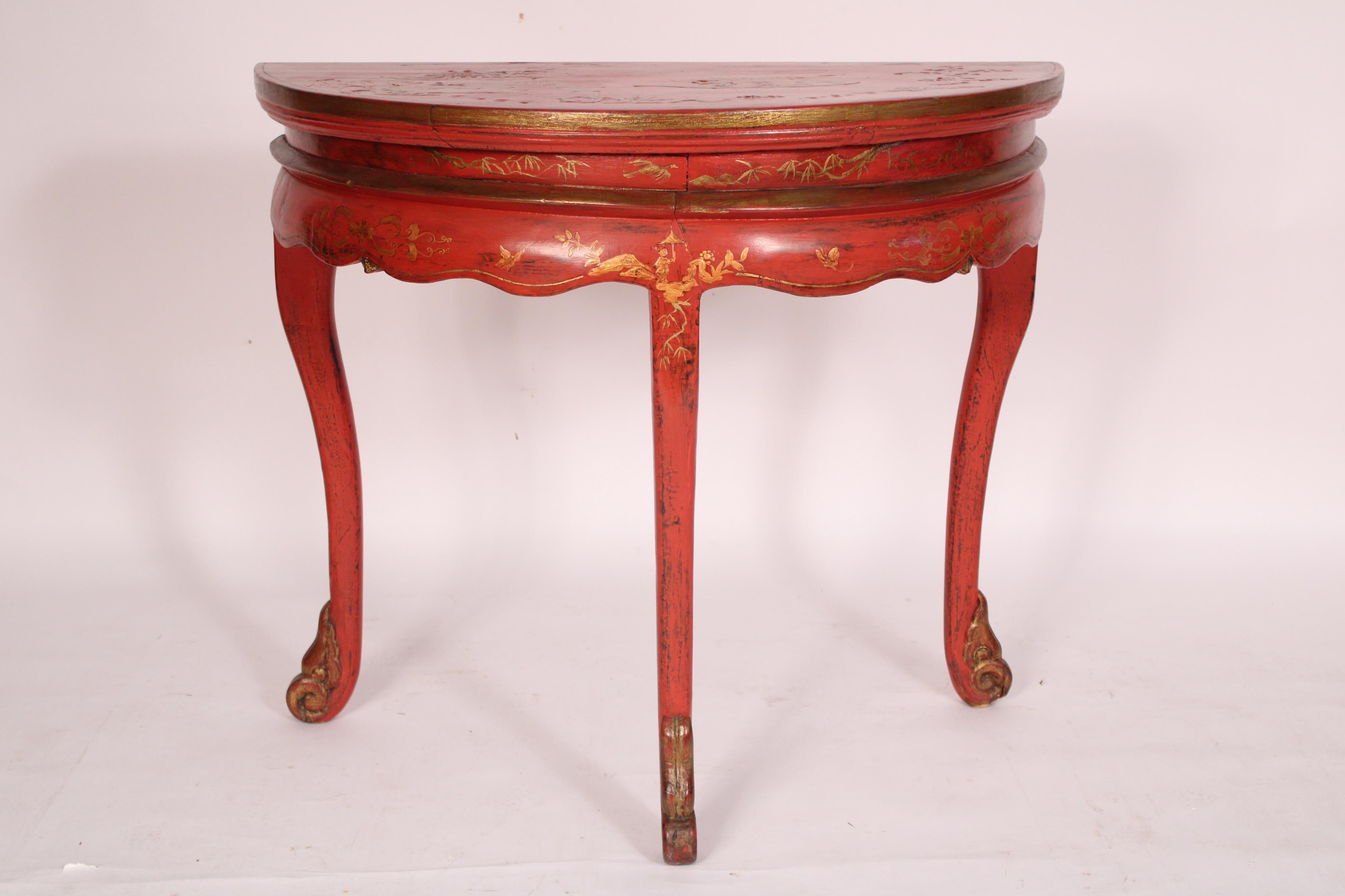 Consolle demi lune cinese decorata a cineserie rossa, circa 1900. Con un piano demi lune con decorazioni cineserie dorate in rilievo, un grembiule smerlato con decorazioni dorate, che poggia su gambe cabriole che terminano con piedi a chiocciola.