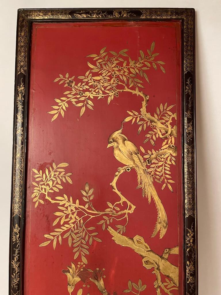 Beautifully realized 19th century Chinese panel with a cockatoo-like bird looking regal sitting in a tree in a landscape with foliage and boulders against a red lacquer background. All enclosed by a black lacquer frame with gilt decoration. You have