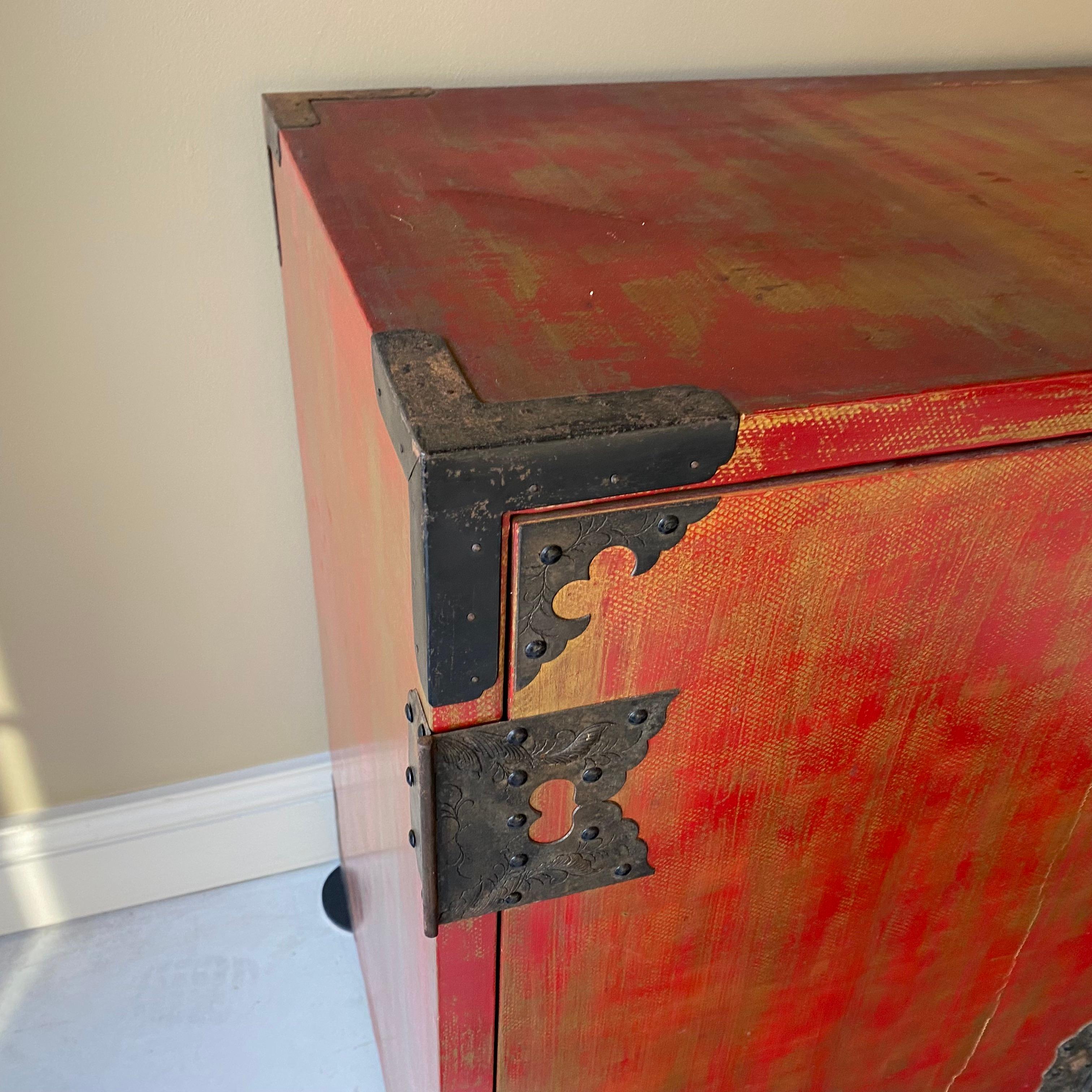 Beautiful Chinese antique Buffet finished in red lacquer and gold leaf. Having 4 door 2 doors connected together slid open with 3 shelves to each side . Finished with hand made iron brackets to the corners and to the front medallion Great Storage.