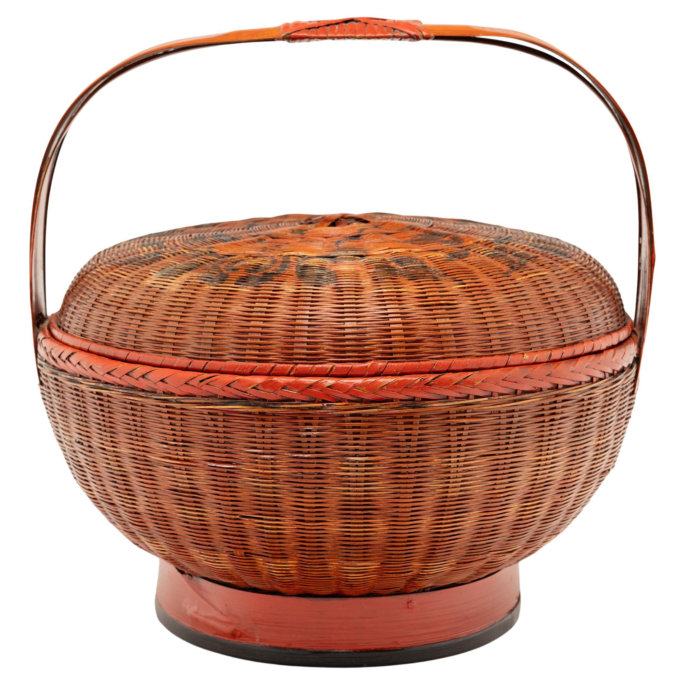 This lacquered Chinese carrying basket impresses with a prim, balanced form of intricately woven split bamboo. A celebratory form traditionally used for carrying food or delivering gifts, the lidded basket has a rounded body elevated by a footed