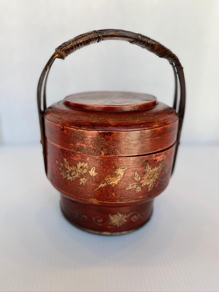 Chinese red lacquer food box red lacquered and hand painted in gold leaf with handle attached.