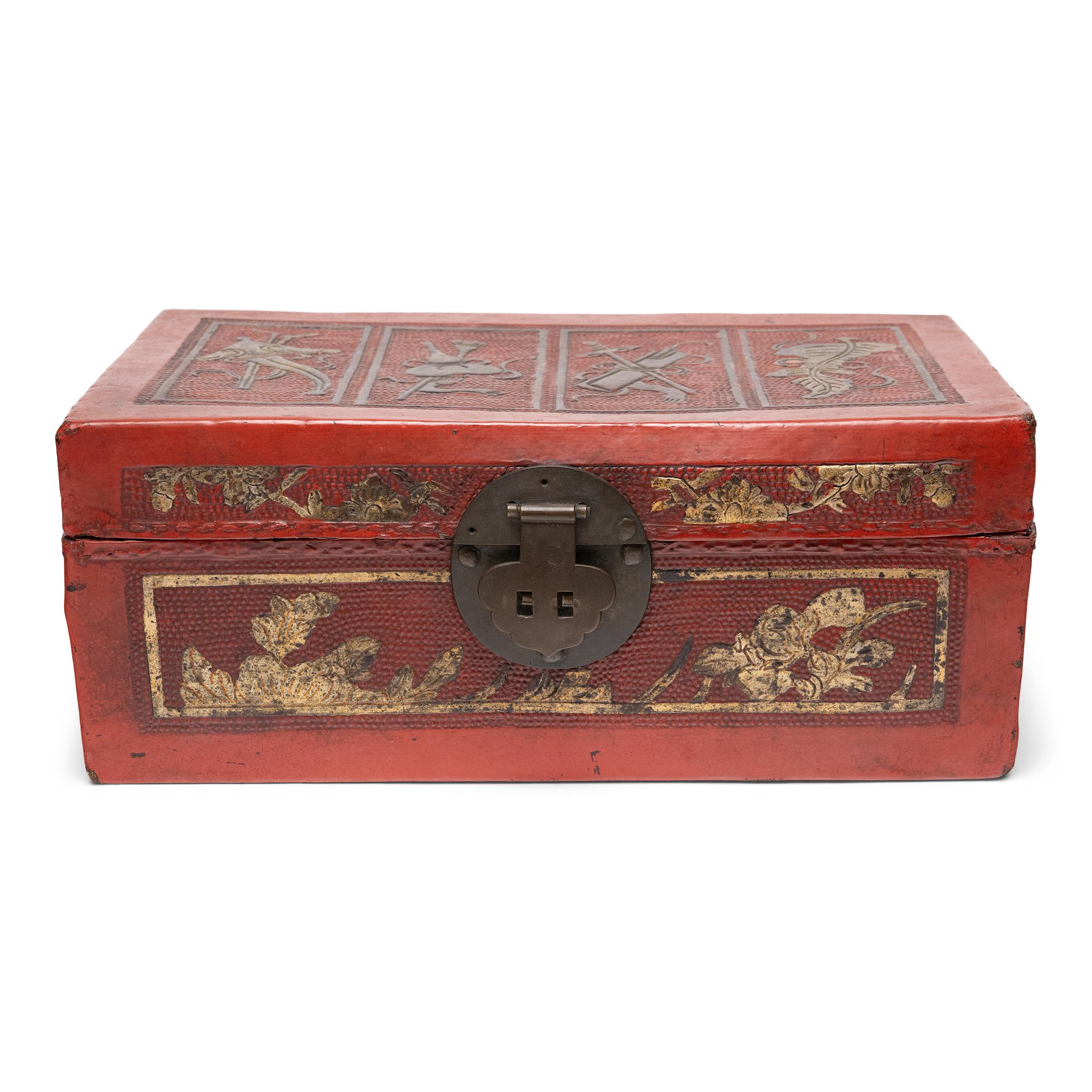 Cette petite boîte à trésors de la fin du XIXe siècle illustre la splendeur somptueuse des arts décoratifs de la dynastie Qing (1644-1911), avec ses embellissements complexes et ses couleurs rouge et or. La boîte rectangulaire est façonnée en cuir