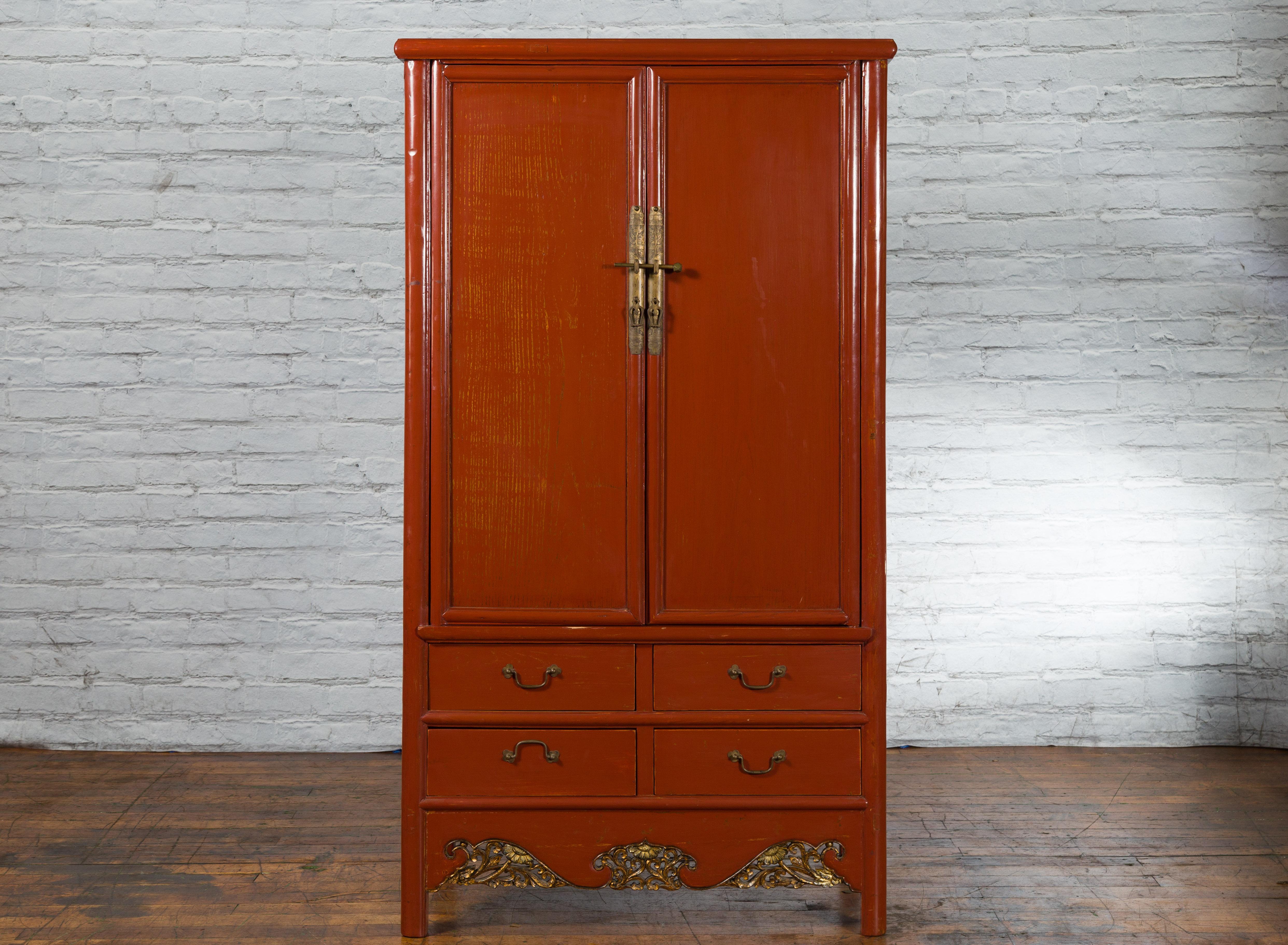 A Chinese Ming Dynasty style red lacquered cabinet from the 19th century, with four drawers, ornate brass hardware and carved apron. Created in China during the Qing Dynasty, this Ming style cabinet attracts our attention with its red lacquer and