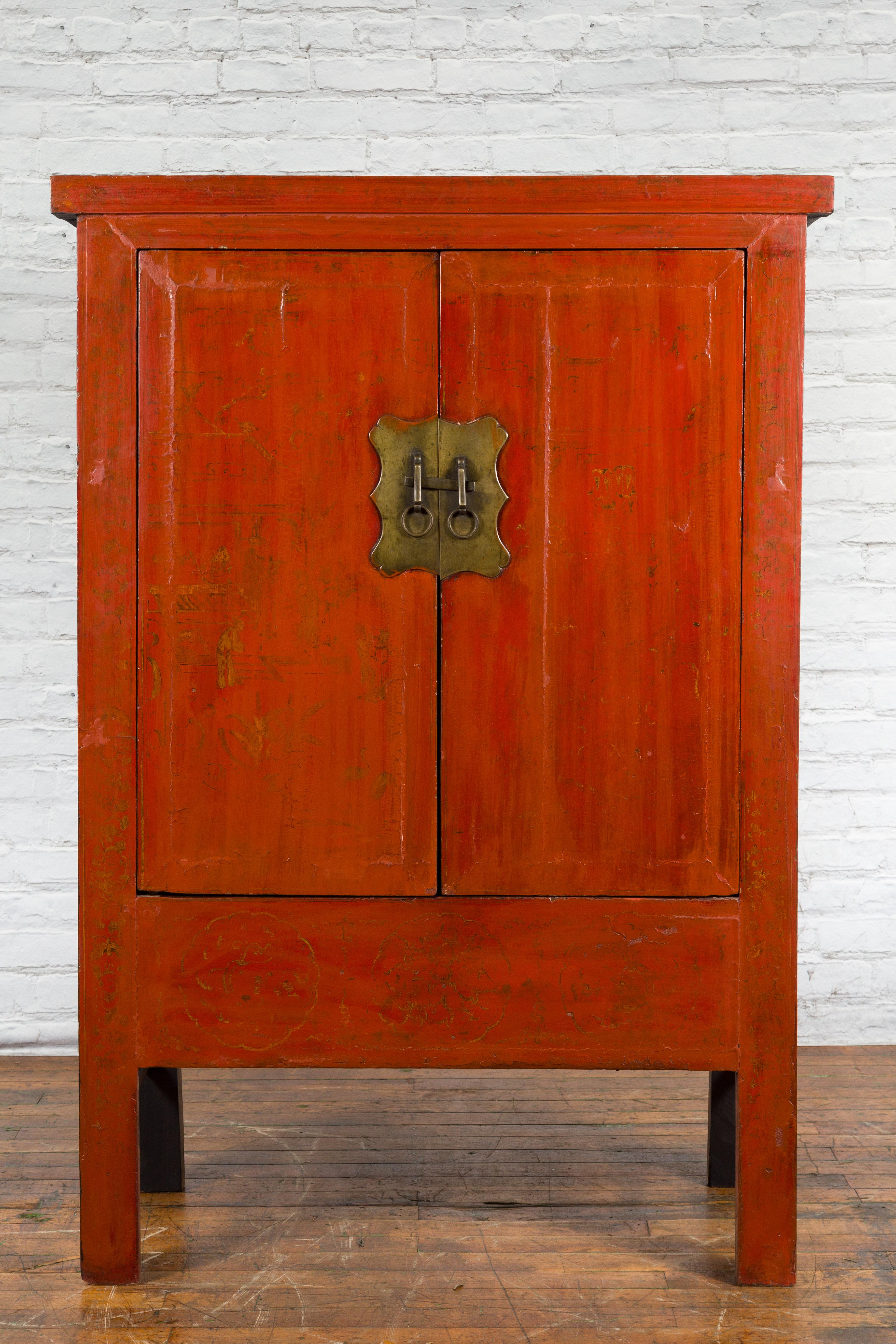 A Chinese Qing Dynasty period red lacquer cabinet from the 19th century with faint hand-painted décor and brass hardware. Created in China during the Qing Dynasty period in the 19th century, this cabinet features a linear silhouette perfectly