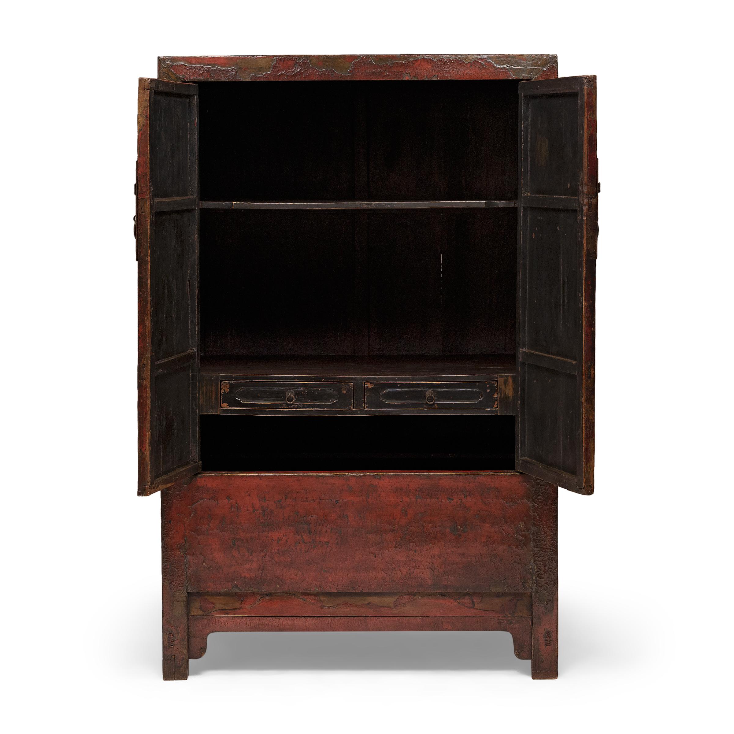 Pièce classique du mobilier chinois, cette étonnante armoire en laque rouge faisait probablement partie de la dot de mariage traditionnelle, offerte au marié par la famille de la mariée et remplie de soies fines, de linge de maison et d'autres