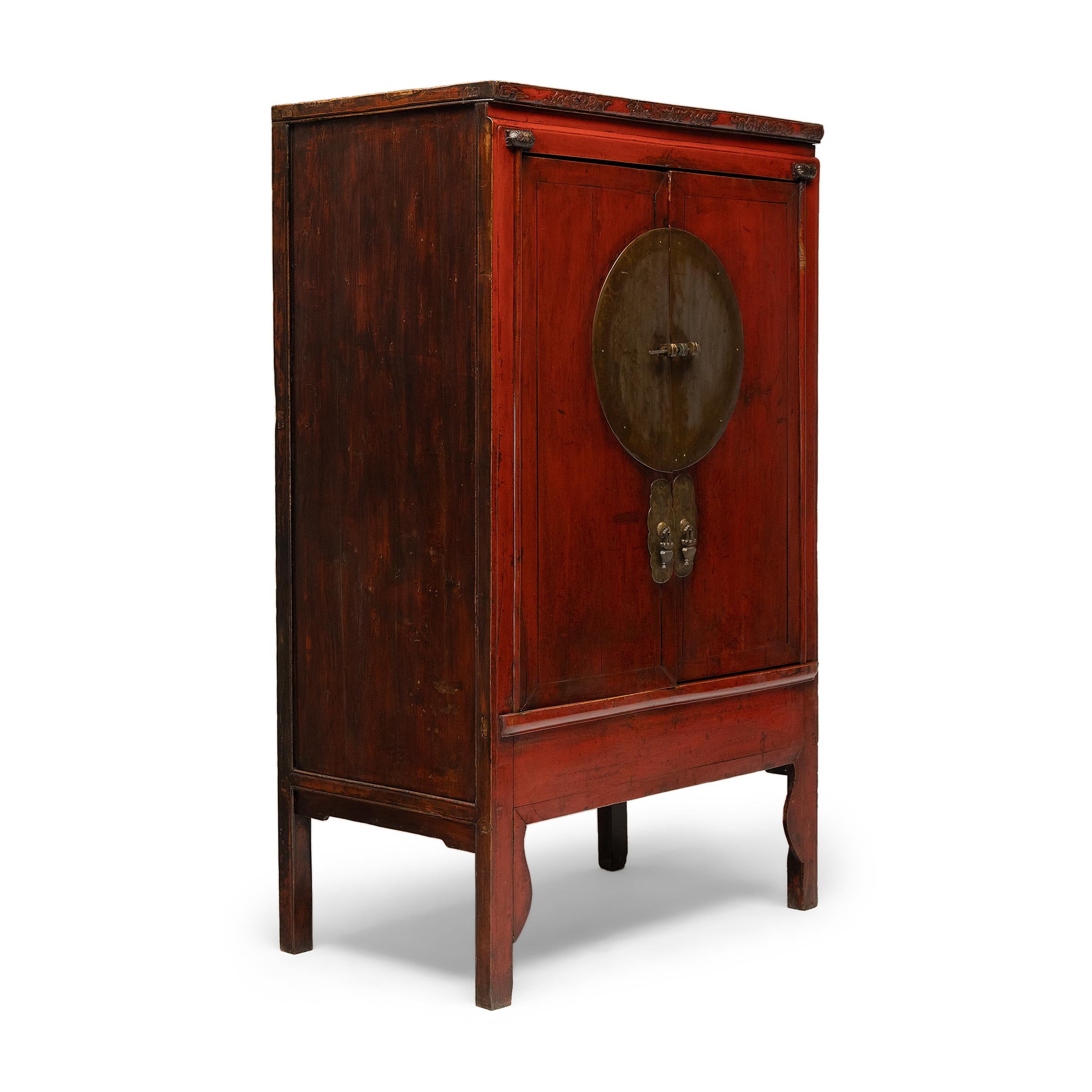 Crafted in the mid-19th century, this striking red lacquer cabinet was likely part of a traditional wedding dowry, bestowed upon the groom by the bride's family filled with fine silks, linens and other gifts. The cabinet has a clean-lined form,