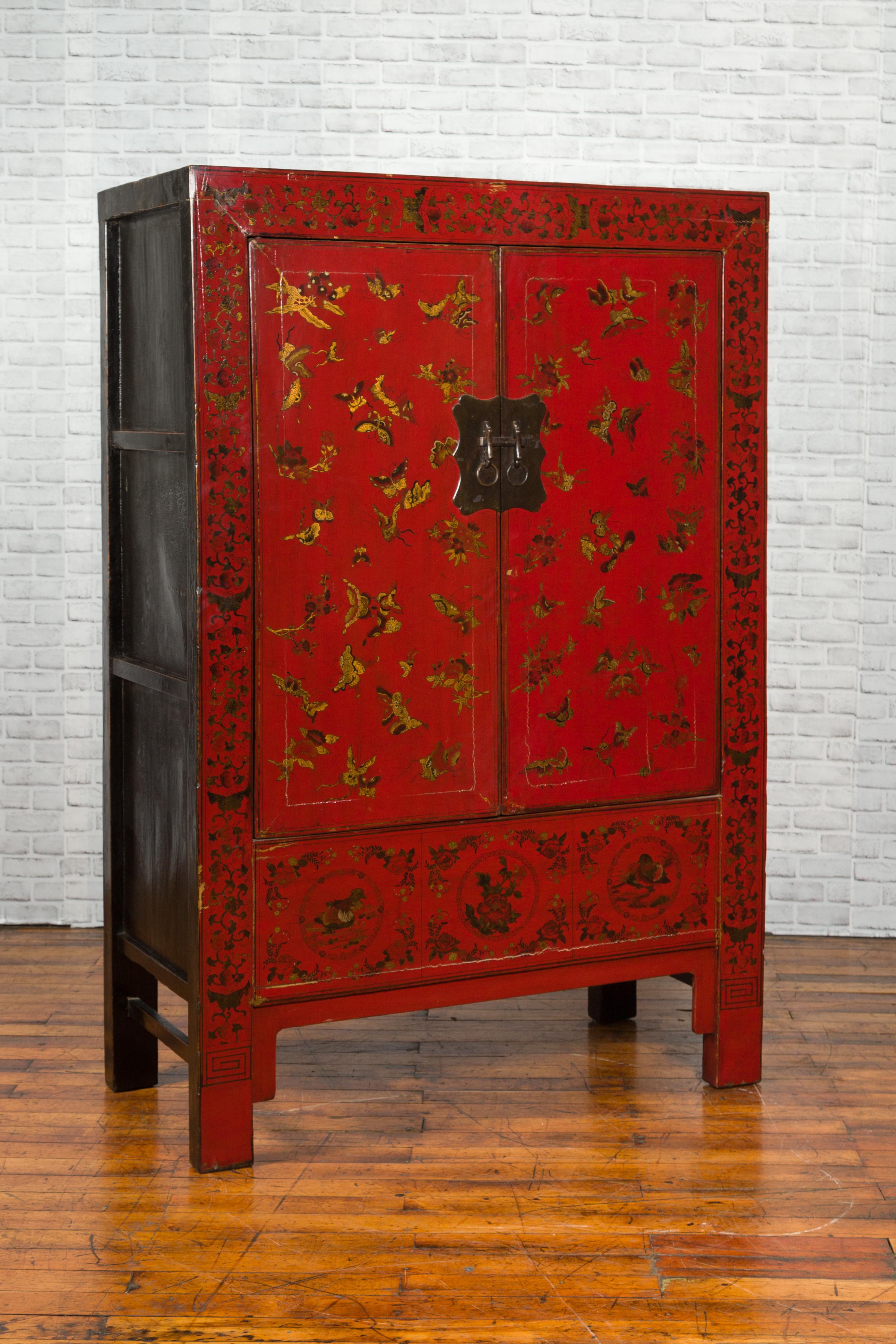 A Chinese Qing dynasty period red lacquered cabinet from the 19th century, with gilt chinoiserie motifs and scalloped brass hardware. Created in China during the Qing dynasty, this cabinet captures our attention with its red lacquered finish