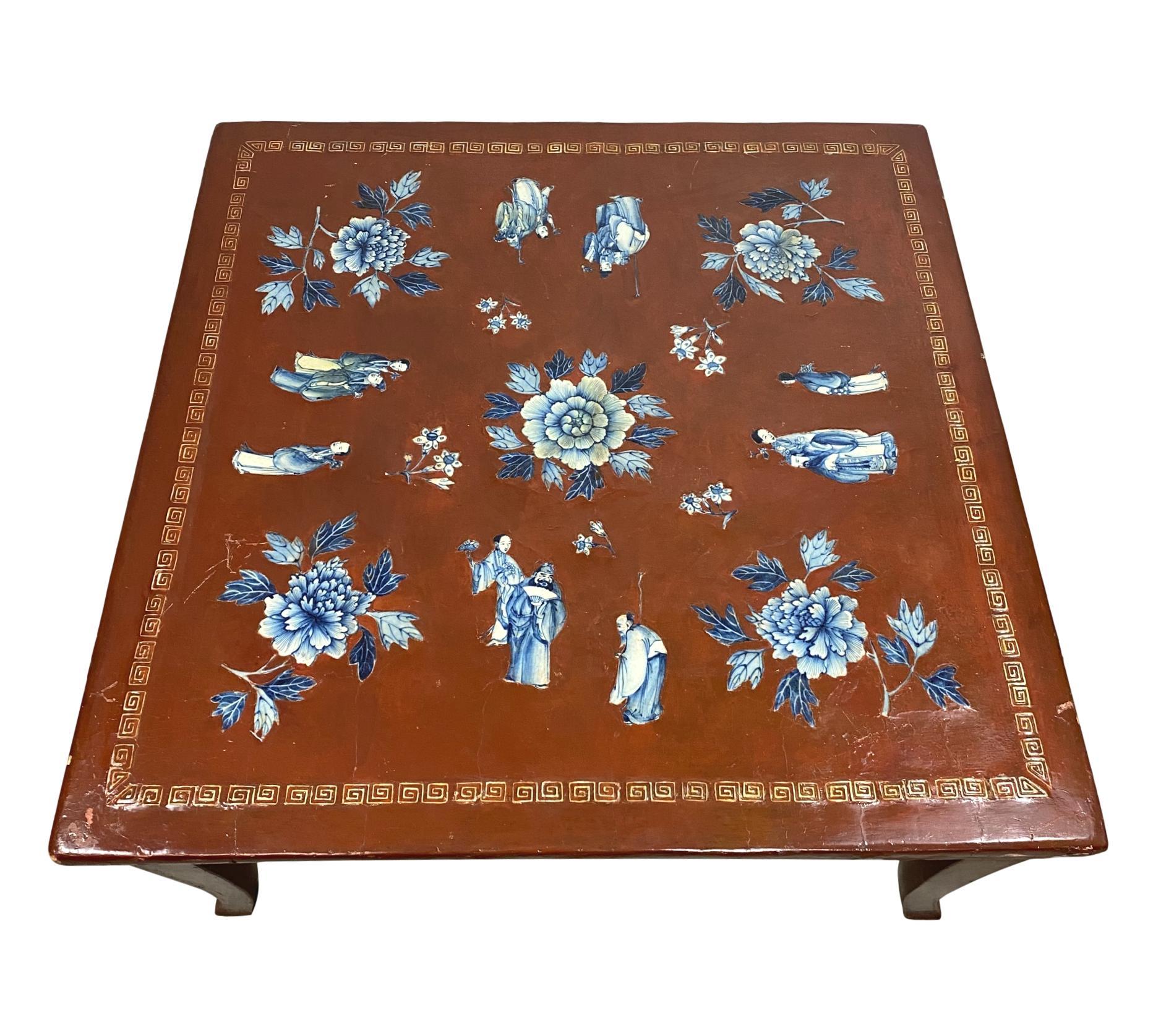 Chinese export red (Cinnabar) lacquered king table or coffee table, the top with applied relief-molded blue and white Cantonese porcelain figures of dignitaries and peonies, the top bordered with Greek key inlaid tiles, with further applied