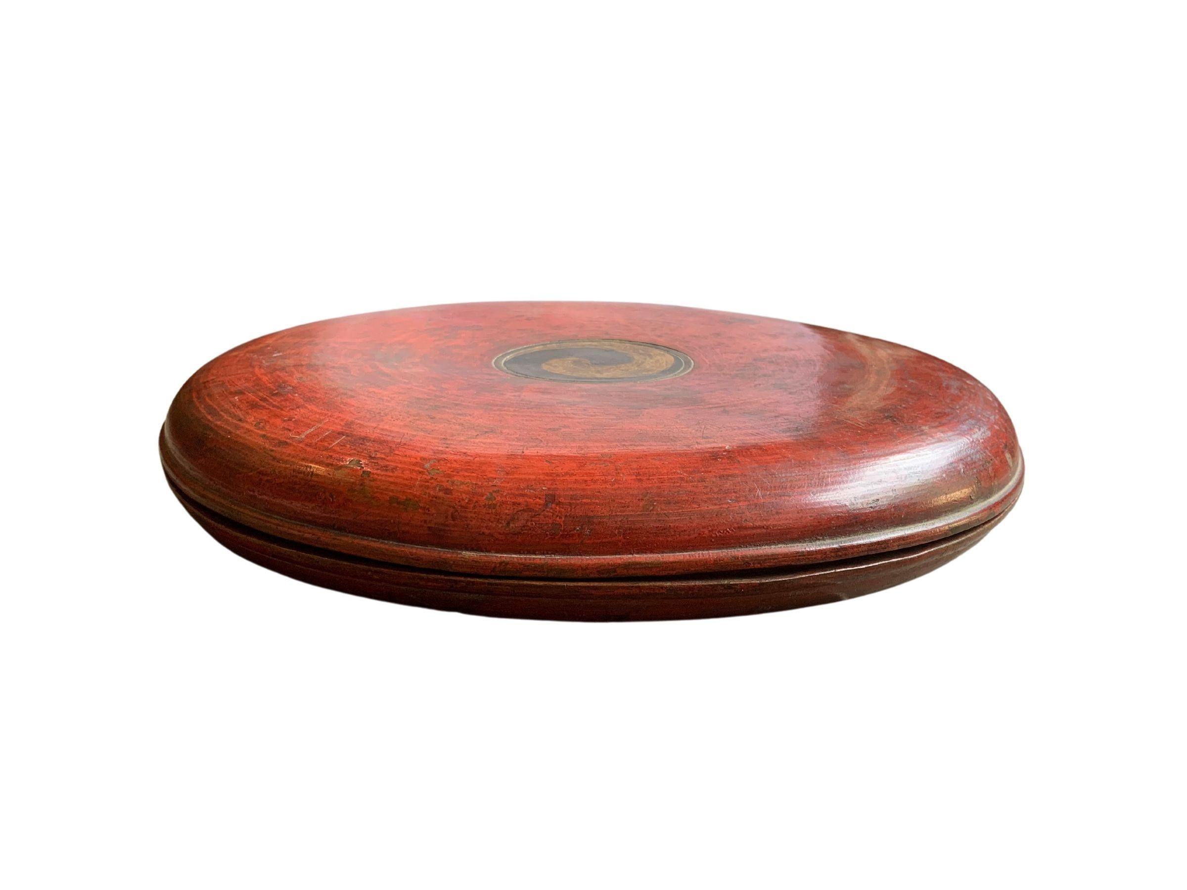 A visibly old red lacquered round wooden box from Qing Dynasty China. The fading of the original lacquer and paintwork over the many years adds to this boxes charm. Once used to serve food (sweets and other deserts) when welcoming people to ones