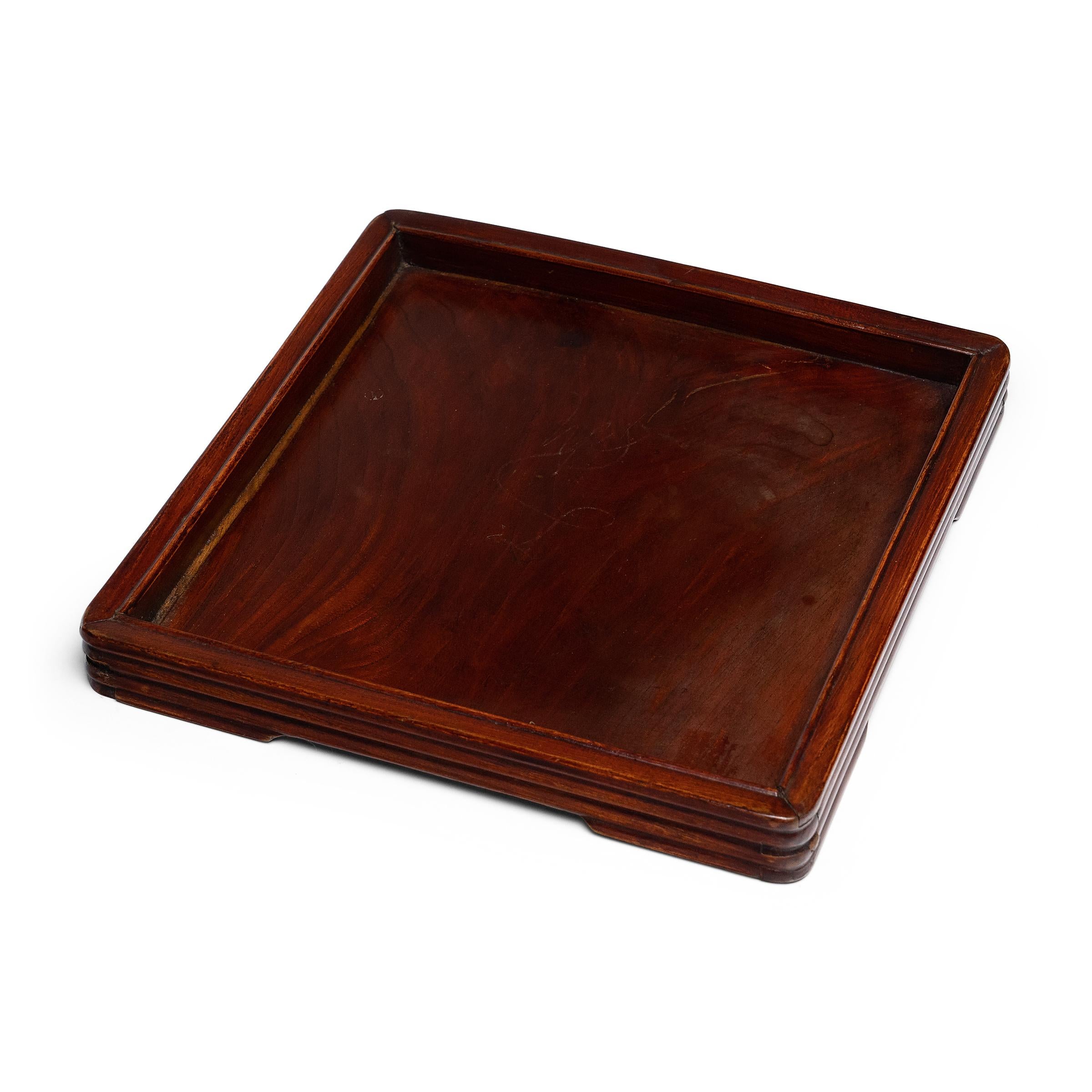 This tea tray from the late 19th century owes its decorative appeal to the beautiful grain of northern elm (yumu) and the warm brown color of its sheer lacquer finish. Once used to serve tea or hold scholarly implements, the shallow tray is