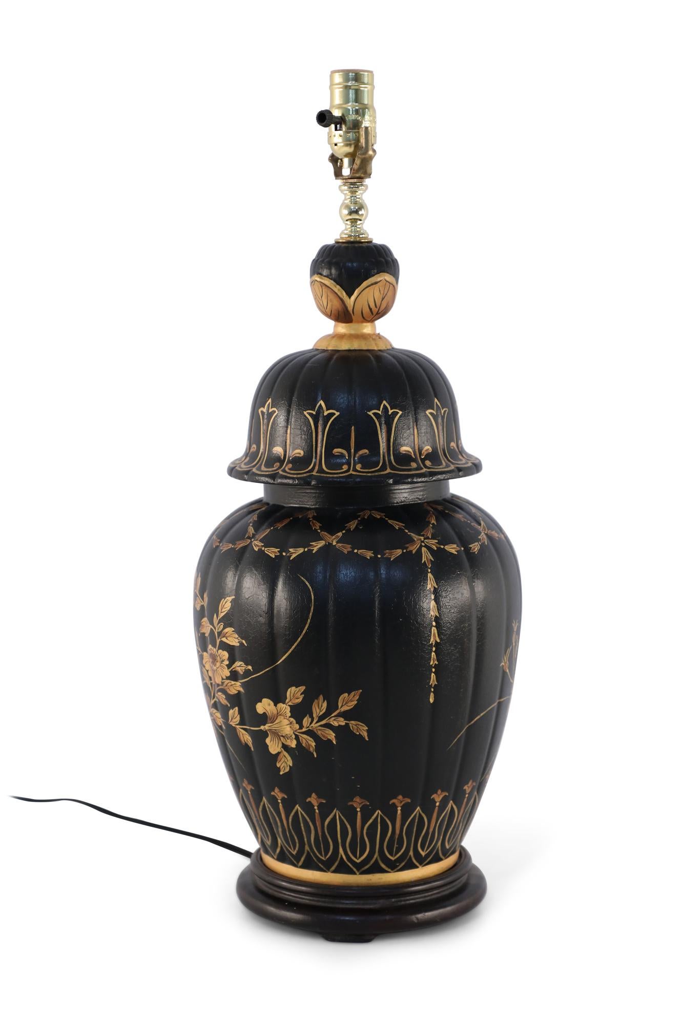 Chinese black porcelain table lamp made from a lidded urn decorated in gold florals, swag foliage, and geometric patterns sitting atop a wooden base fitted with brass hardware.