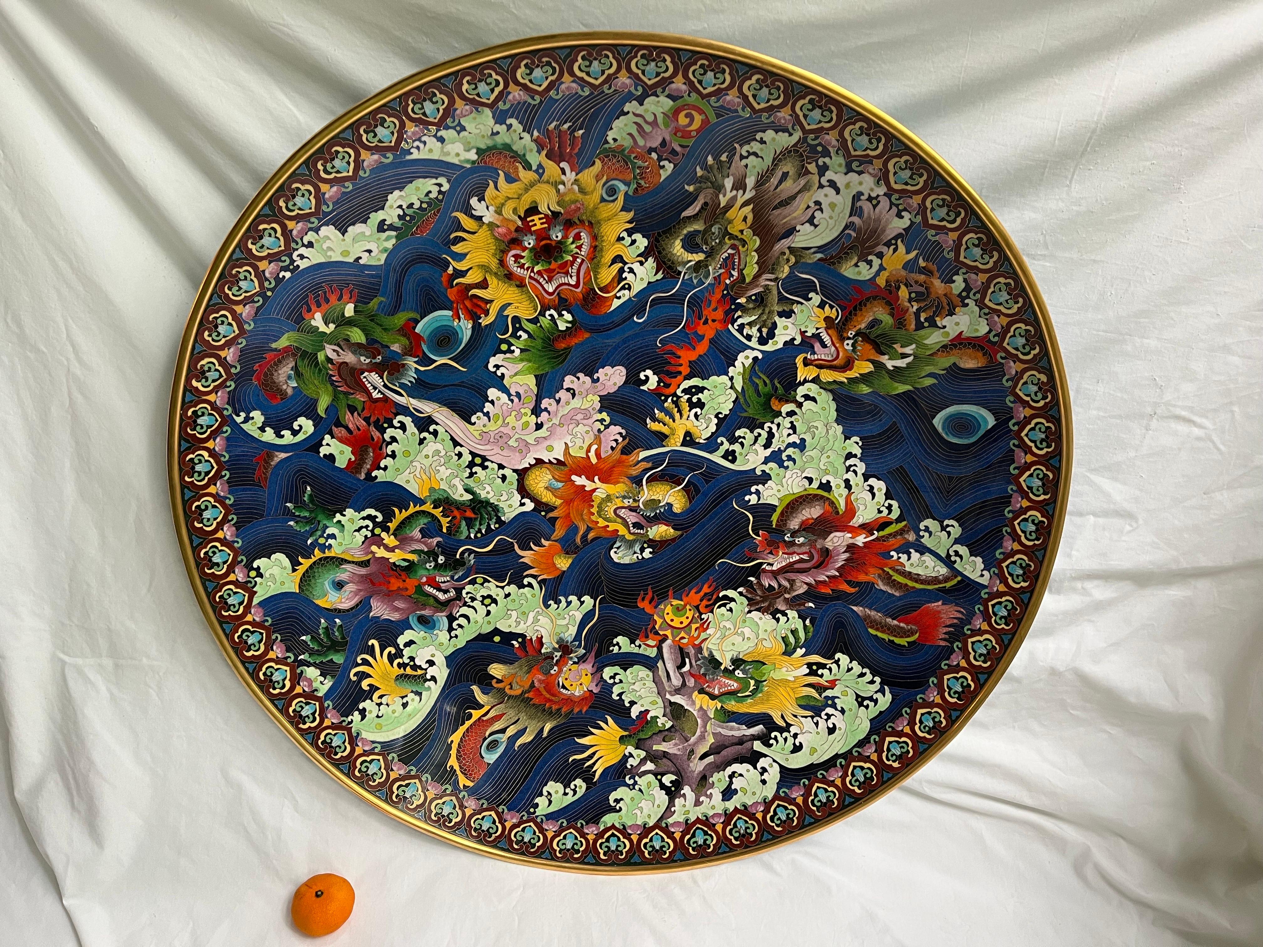 A monumental Chinese Republic cloisonne enamel on metal charger depicting the story of the Nine Dragons. Measuring just over thirty inches in diameter and just under four inches in height, this beautifully detailed and richly colored charger (or